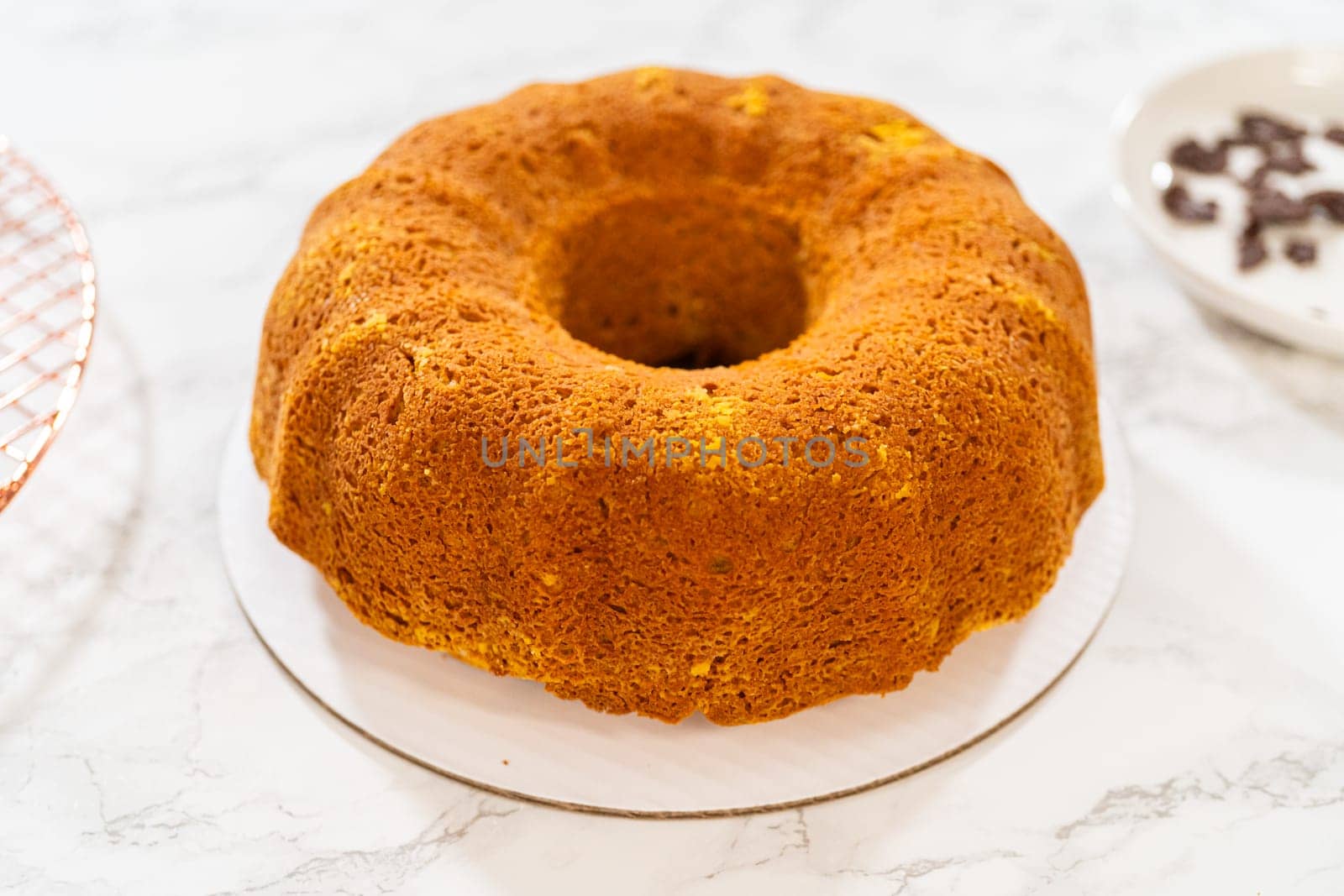 Icing the pumpkin bundt cake with cream cheese frosting and decorating it with chocolate leaves.