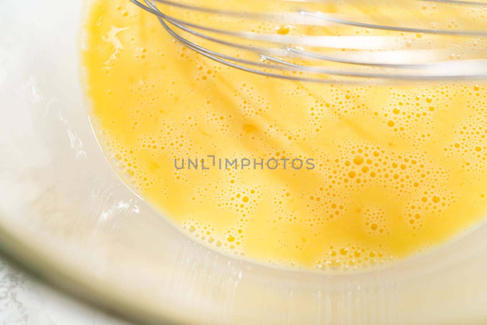 A close-up view of expertly blended ingredients in a large mixing bowl for a mouthwatering homemade pumpkin bundt cake.