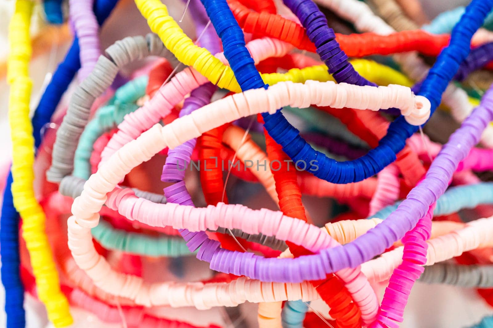 A vibrant collection of clay beads, neatly arranged by color on a white table, ready to inspire young crafters to create their own unique bracelets.