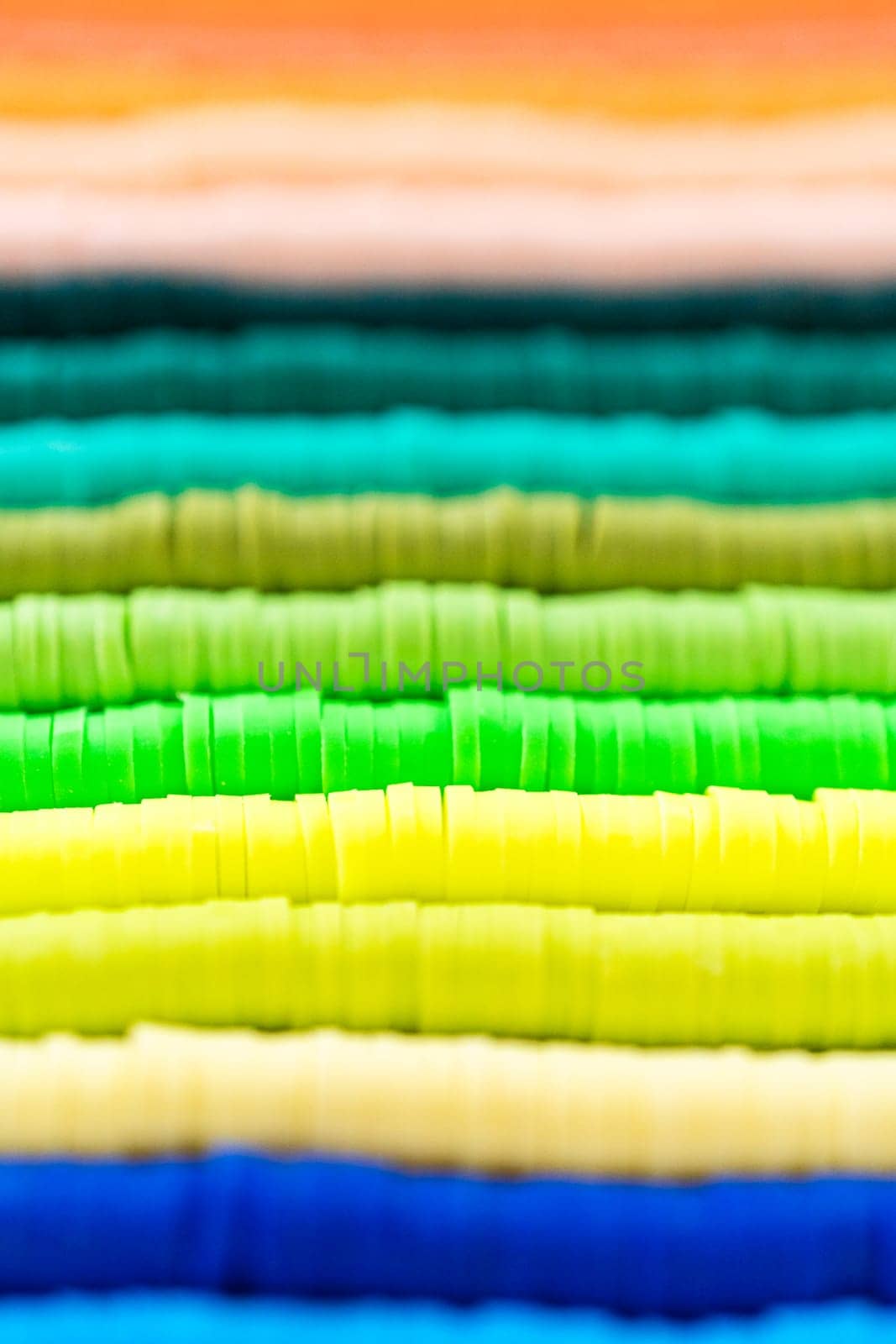 A vibrant collection of clay beads, neatly arranged by color on a white table, ready to inspire young crafters to create their own unique bracelets.