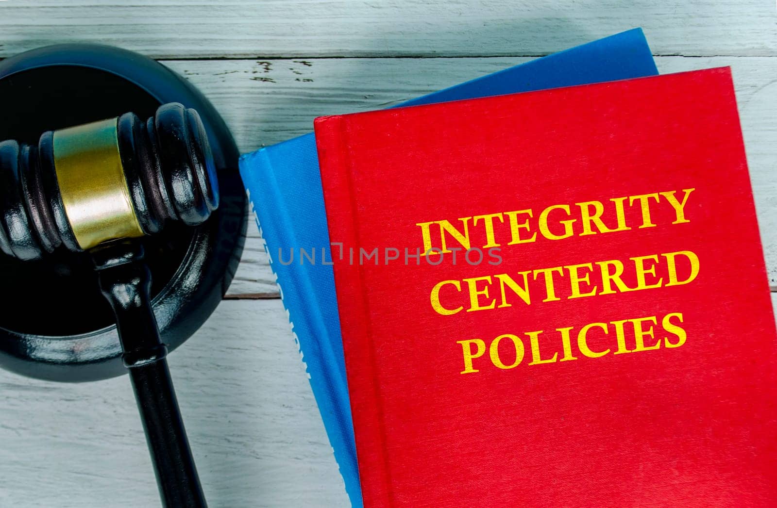 Top view of Integrity Centered policies text on red cover book with gavel background.