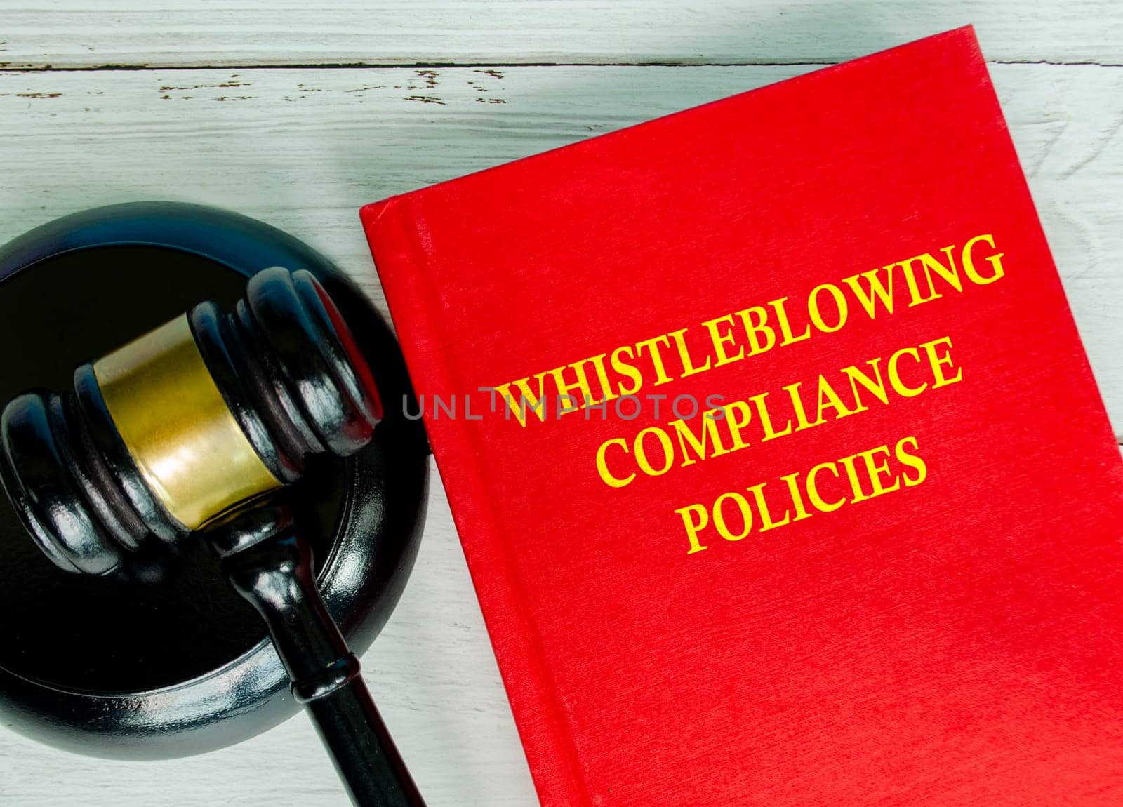 Top view of Whistleblowing Compliance Policies book with gavel background.