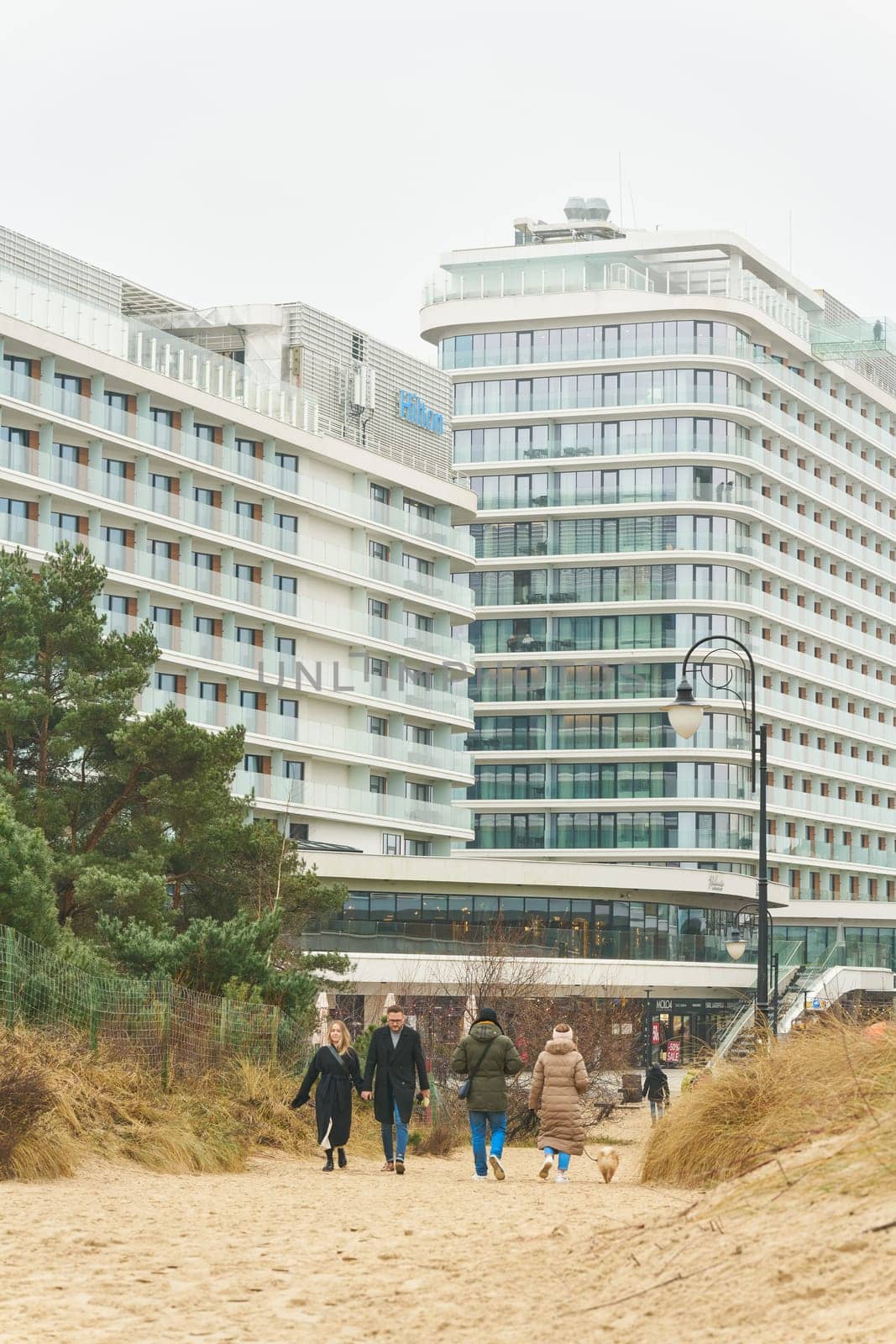 Swinoujscie, Poland – December 26, 2024: Hotels and some vacationers on the beach of Swinoujscie, Swinemunde on the Polish Baltic Sea coast
