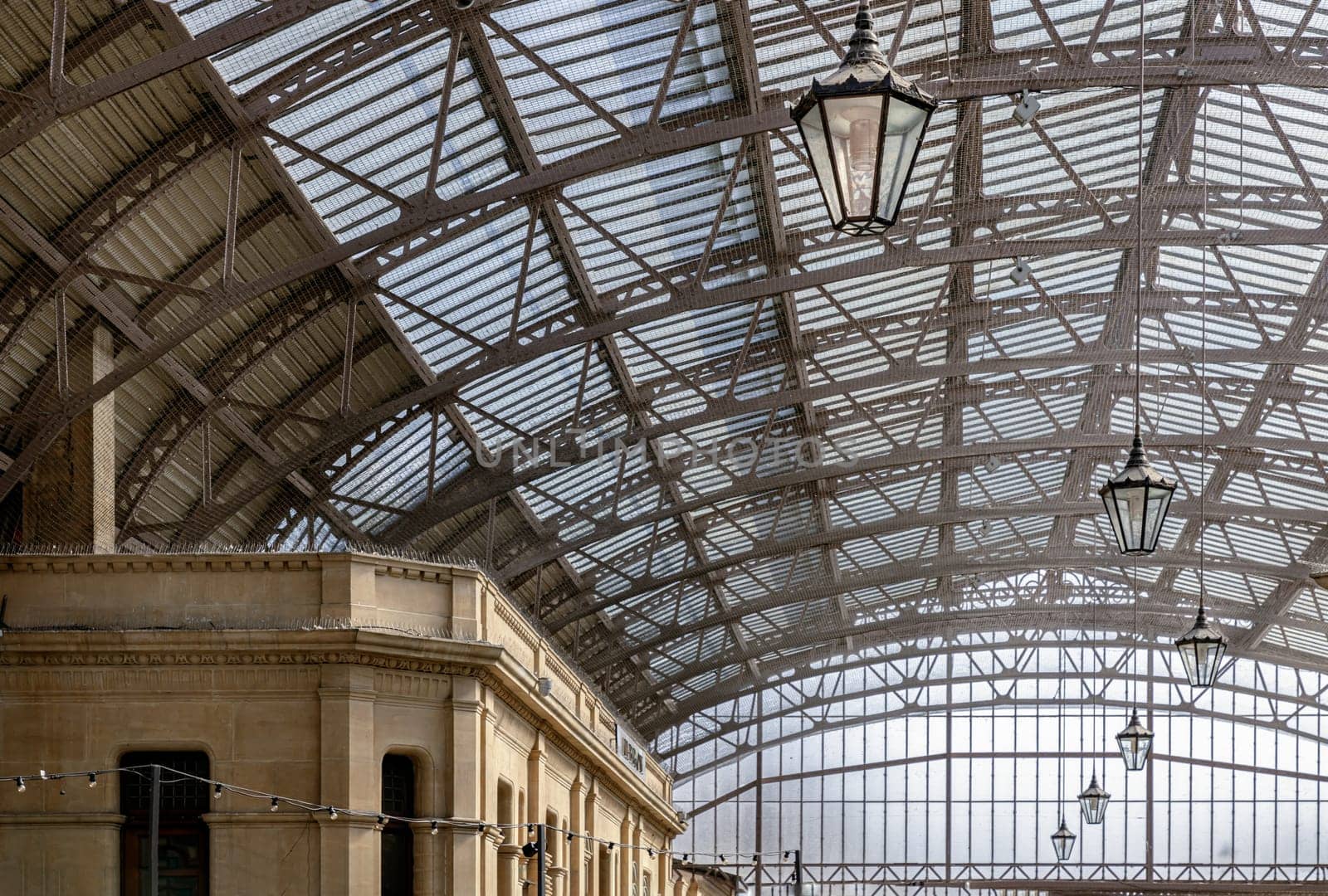 Windsor, UK - Apr 3, 2025 - The vintage iron glass roof with Lamps on the ceiling of Windsor Royal Shopping complex. Perspective view of Metallic framework arch roof with ceiling hanging lamp, Victorian Architecture, use it as your Wallpaper, Poster and Space for text, Selective focus.