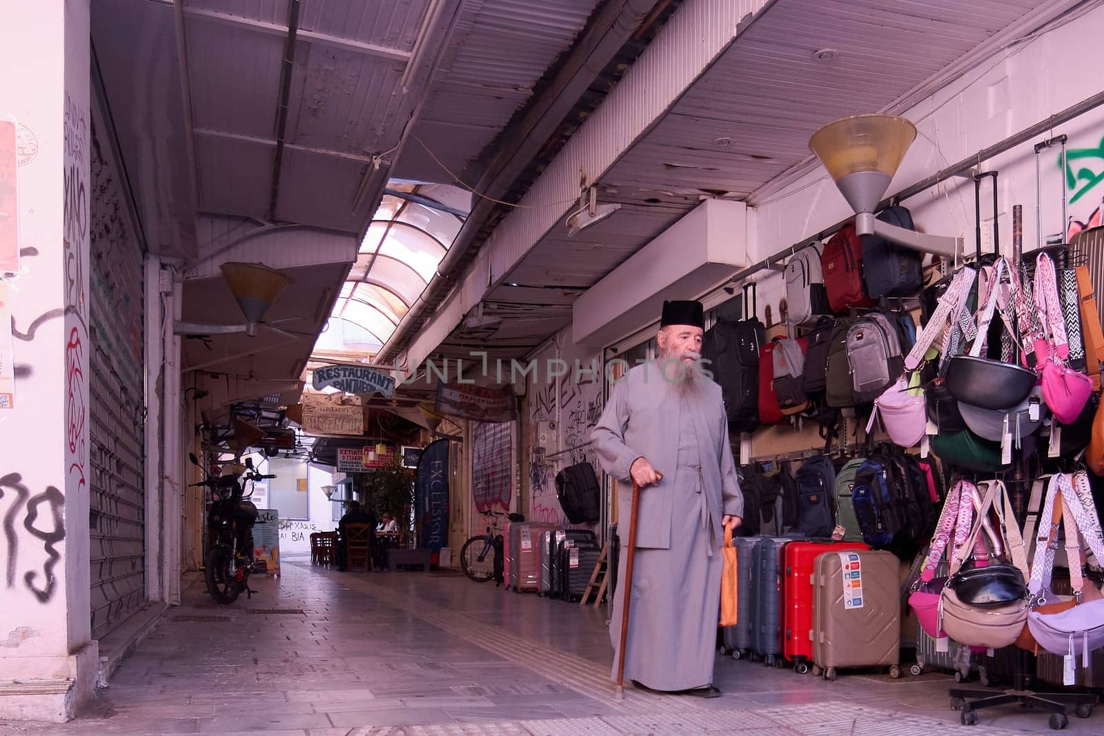 Crete, Greece - April 5, 2025: Bustling covered market featuring shops with bags, backpacks, and suitcases, alongside graffiti-covered walls and tiled floors, creating a vibrant local experience.