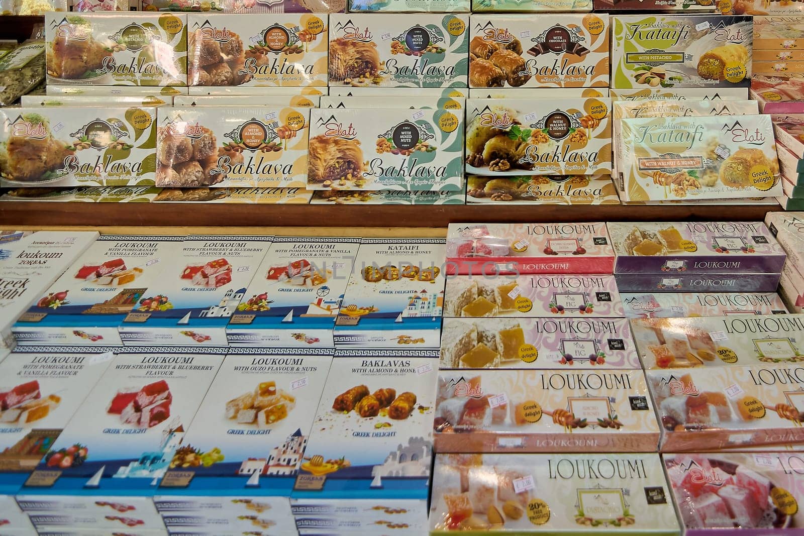 Crete, Greece - April 5, 2025: Vibrant display of traditional Greek sweets including baklava, kataifi, and loukoumi, packed in colorful boxes with cultural and regional designs.