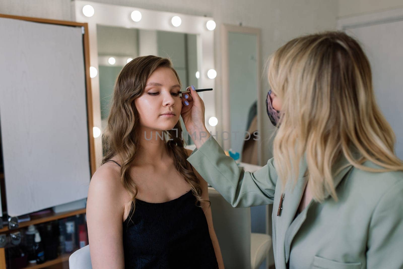Makeup artist applies lipstick. Hand of make-up master, painting lips of a young beauty model.