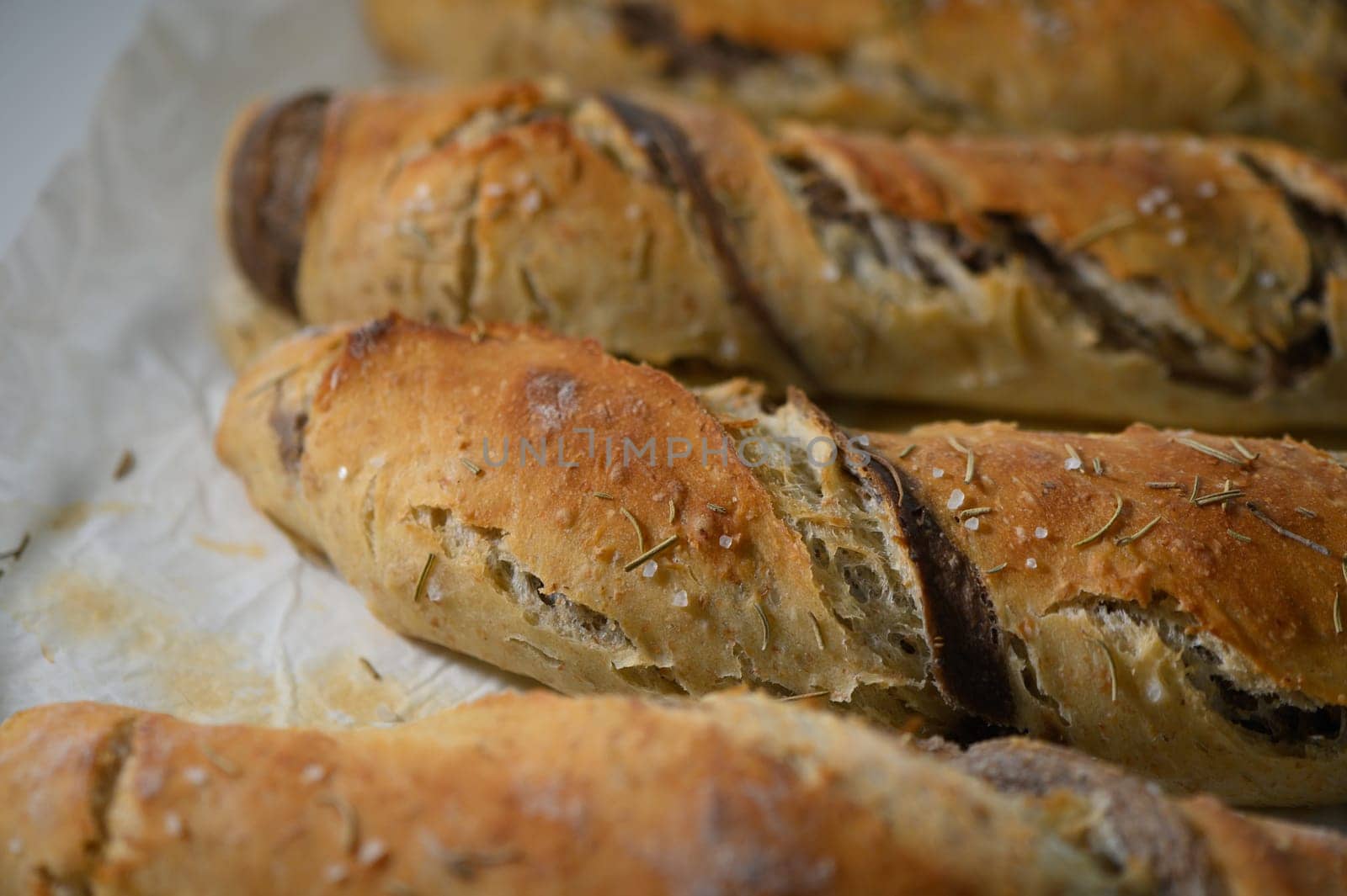 These delightful, freshly baked artisan bread loaves are adorned with a golden crust and sprinkled with aromatic herbs, exuding irresistible warmth and fragrance in a cozy kitchen setting.