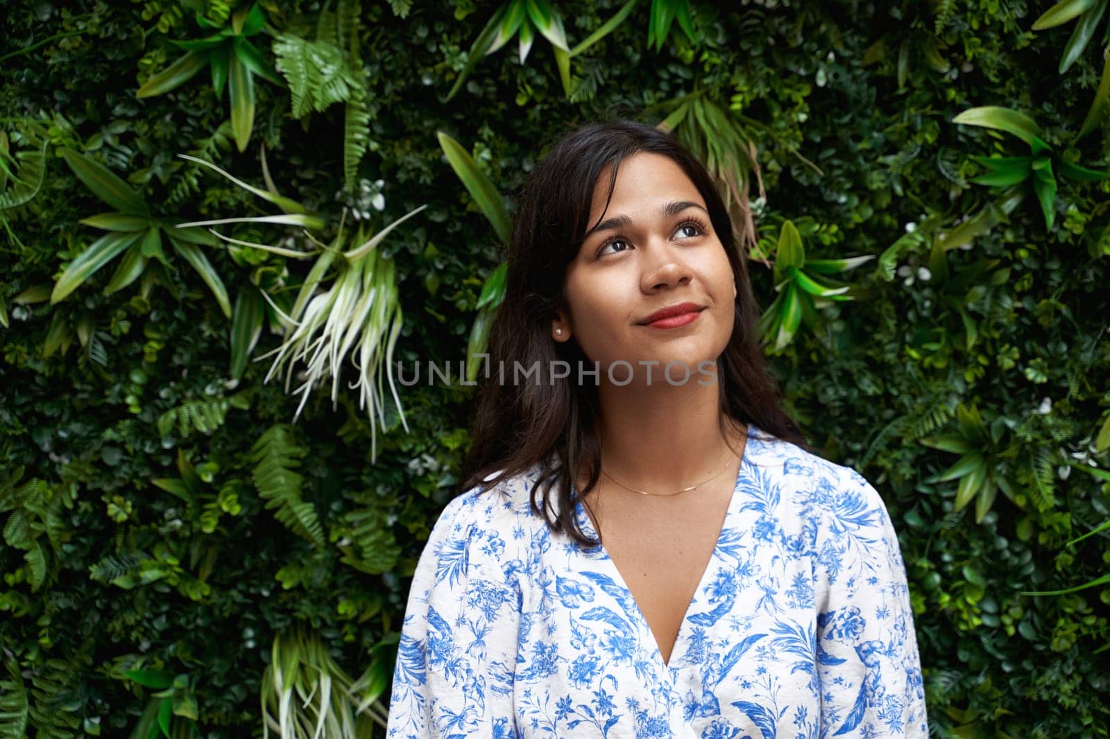 Beautiful young mixed race woman portrait looking up on tropical foliage background