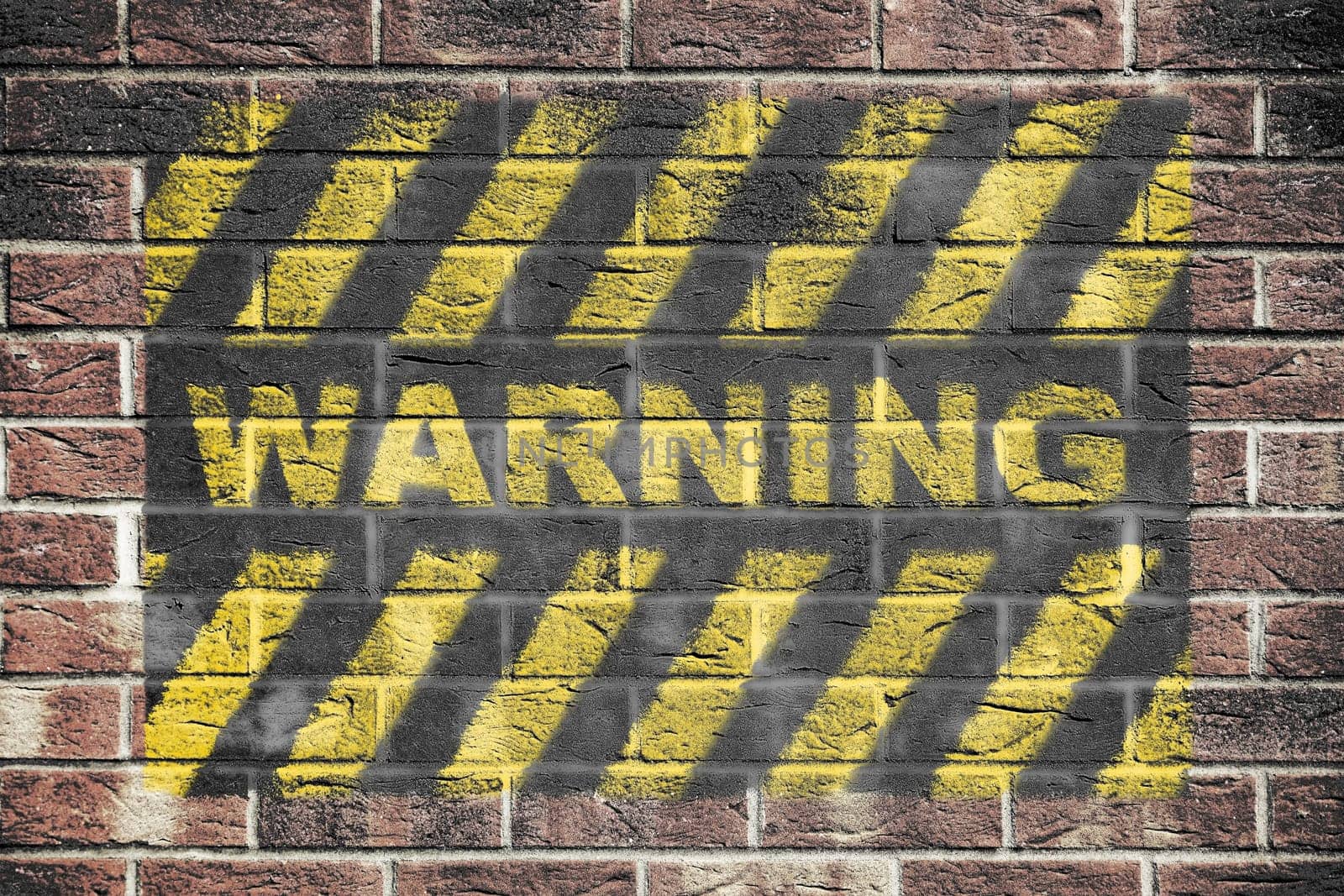 A Warning danger sign with yellow and black stripes on brick wall background