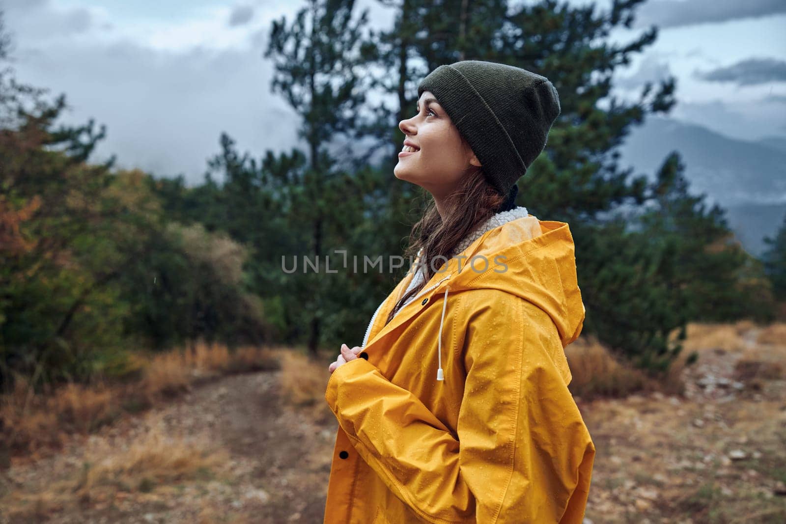 A woman in a yellow raincoat standing on a hill overlooking the majestic mountains in the background Beauty of nature travel scene