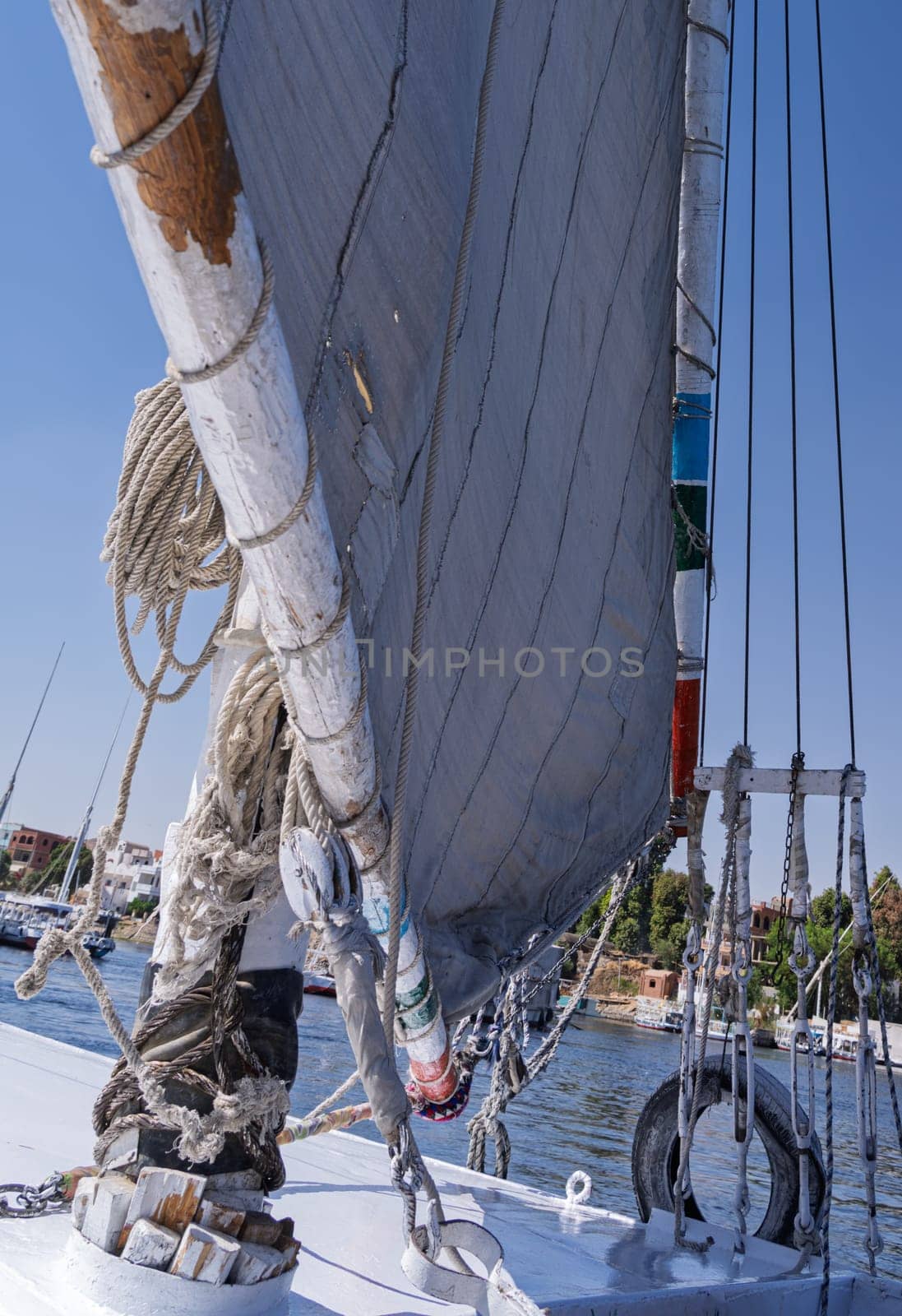 Details of ropes, mast and repaired sailcloth sail on worn felucca boat ready for cruise on Nile