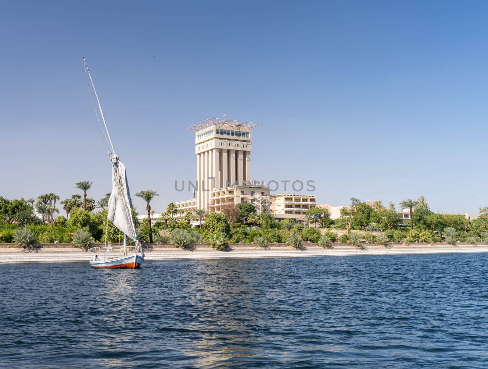 Aswan, Egypt - 4 November 2024: Movenpick Hotel in Elephantine, by the Nile. Felluca sails by the resort