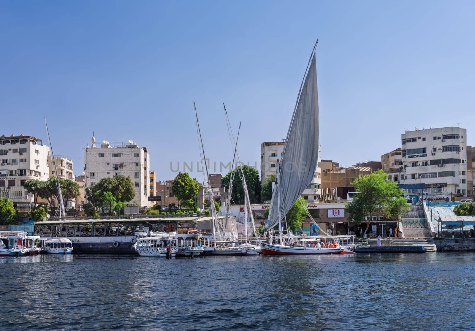 Aswan, Egypt - 4 November 2024: Felucca leaves the dock with other tour boats alongside for a cruise on the Nile