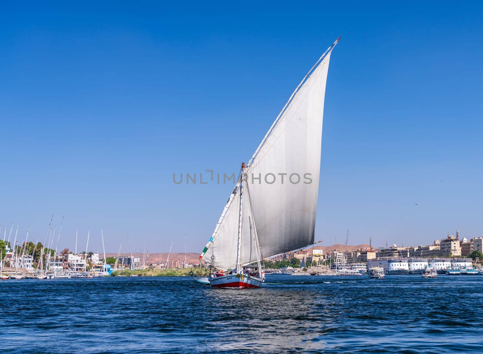 Felucca sailboat sailing upstream with a full sail for a cruise on the Nile in Aswan Egypt