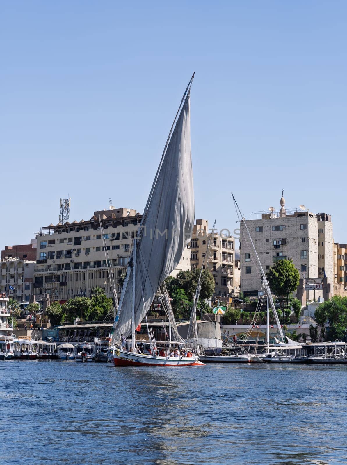 Aswan, Egypt - 4 November 2024: Felucca leaves the dock with other tour boats alongside for a cruise on the Nile