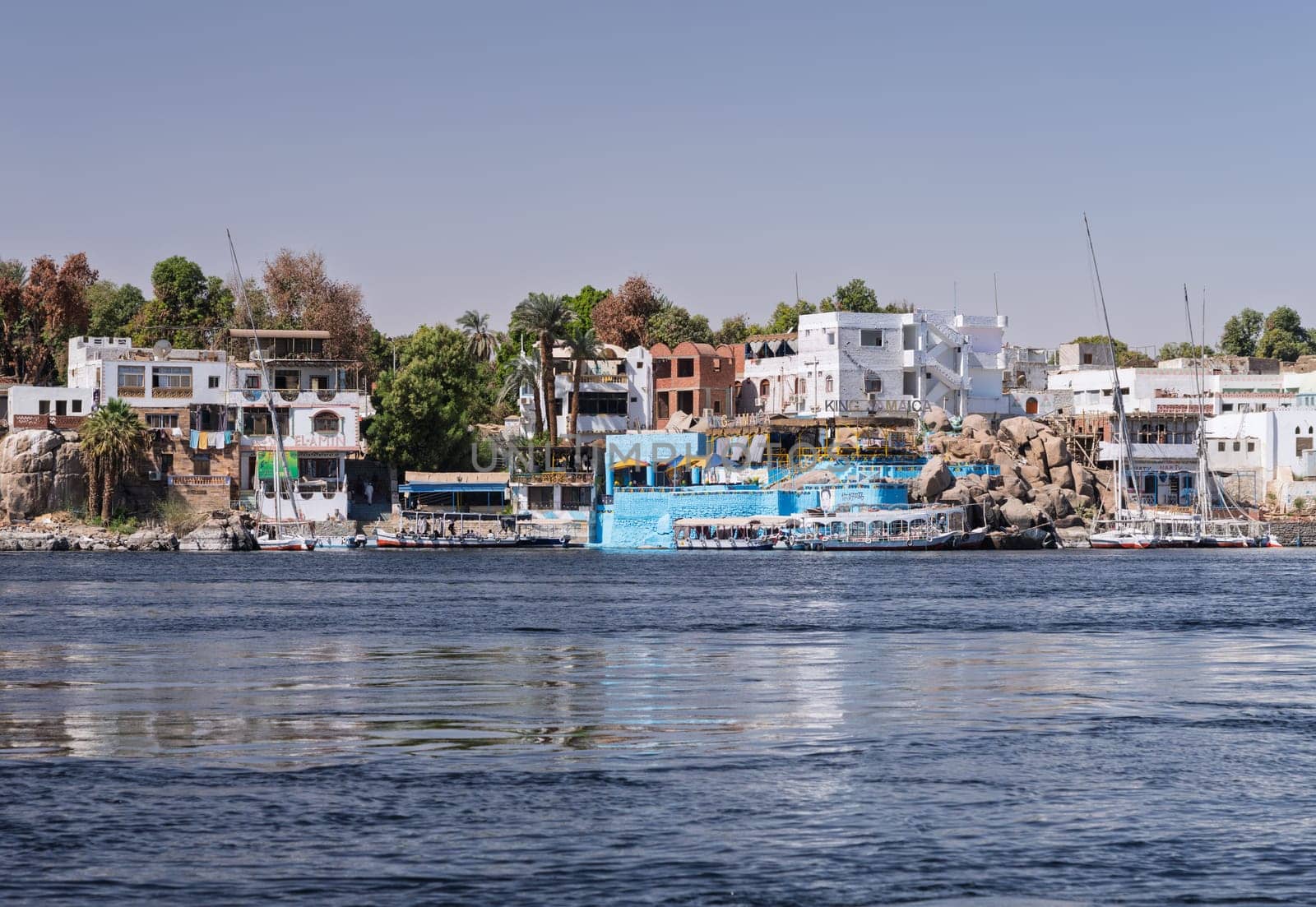 Aswan, Egypt - 4 November 2024: Bars and restaurants including King Jamaica line the shores of Nile with ferry boats