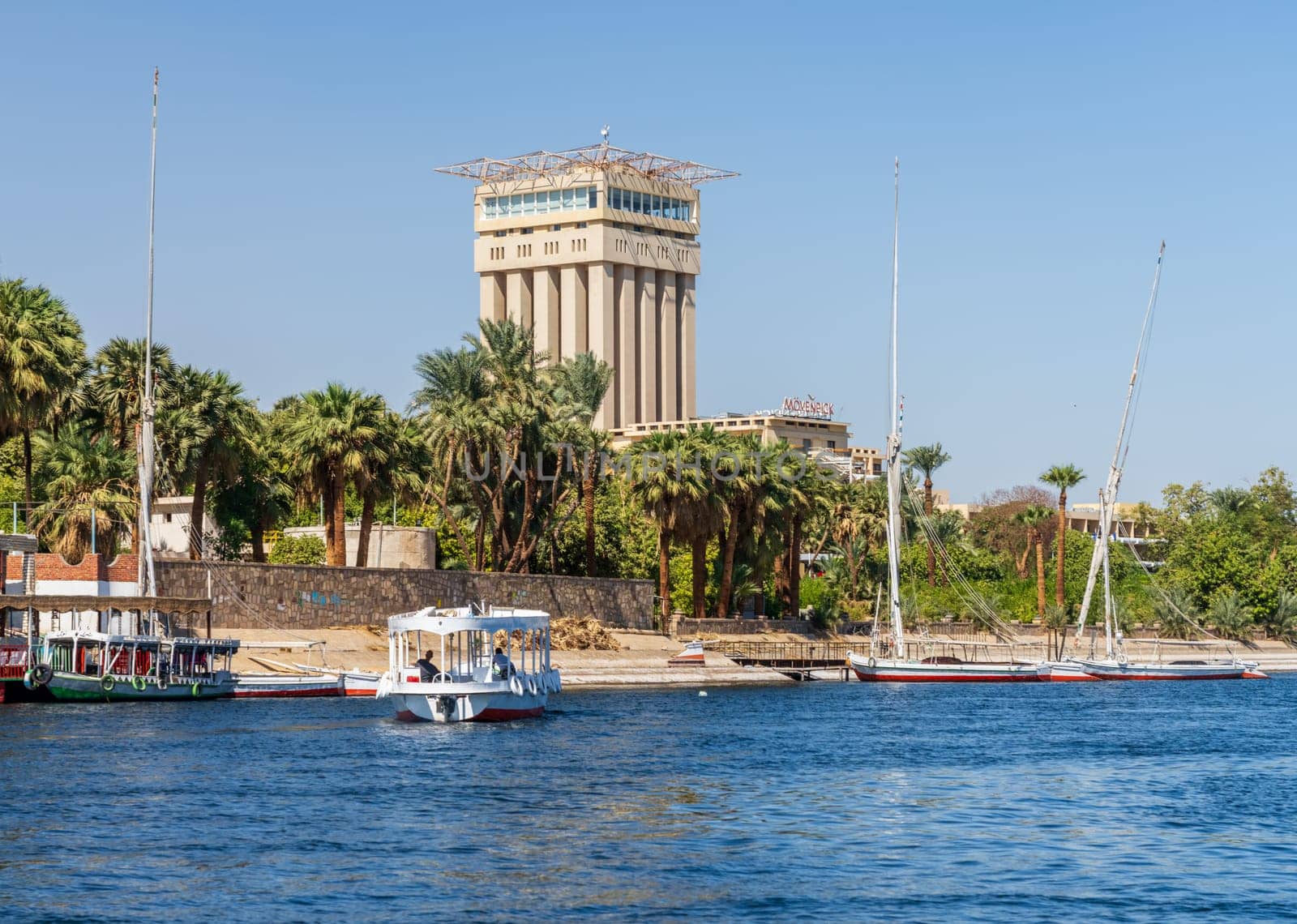 Aswan, Egypt - 4 November 2024: Movenpick Hotel in Elephantine, by the Nile. Felluca docked by the resort