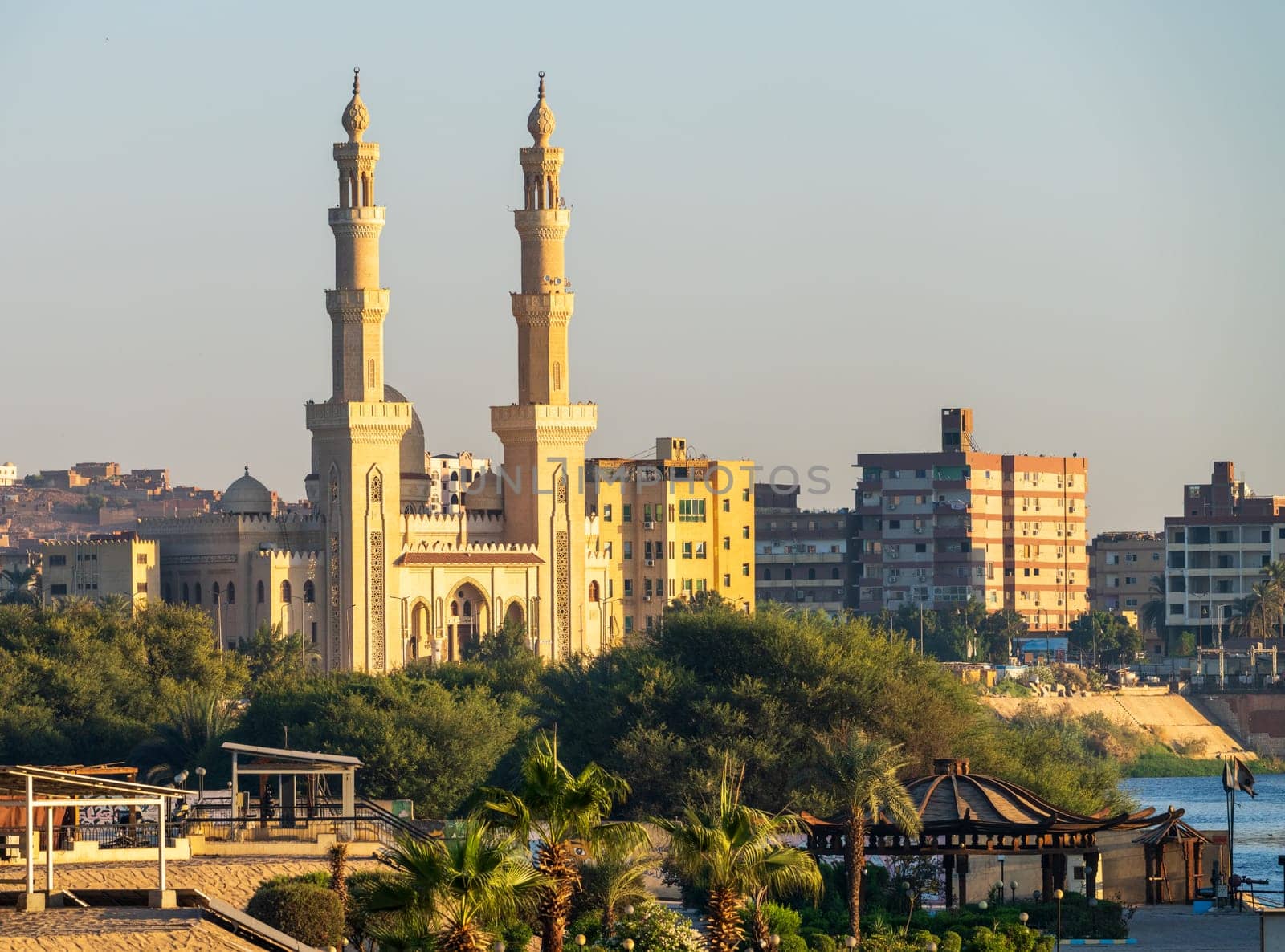 The setting sun illuminates a majestic mosque in Aswan, Egypt with warm light on ts iconic minarets.