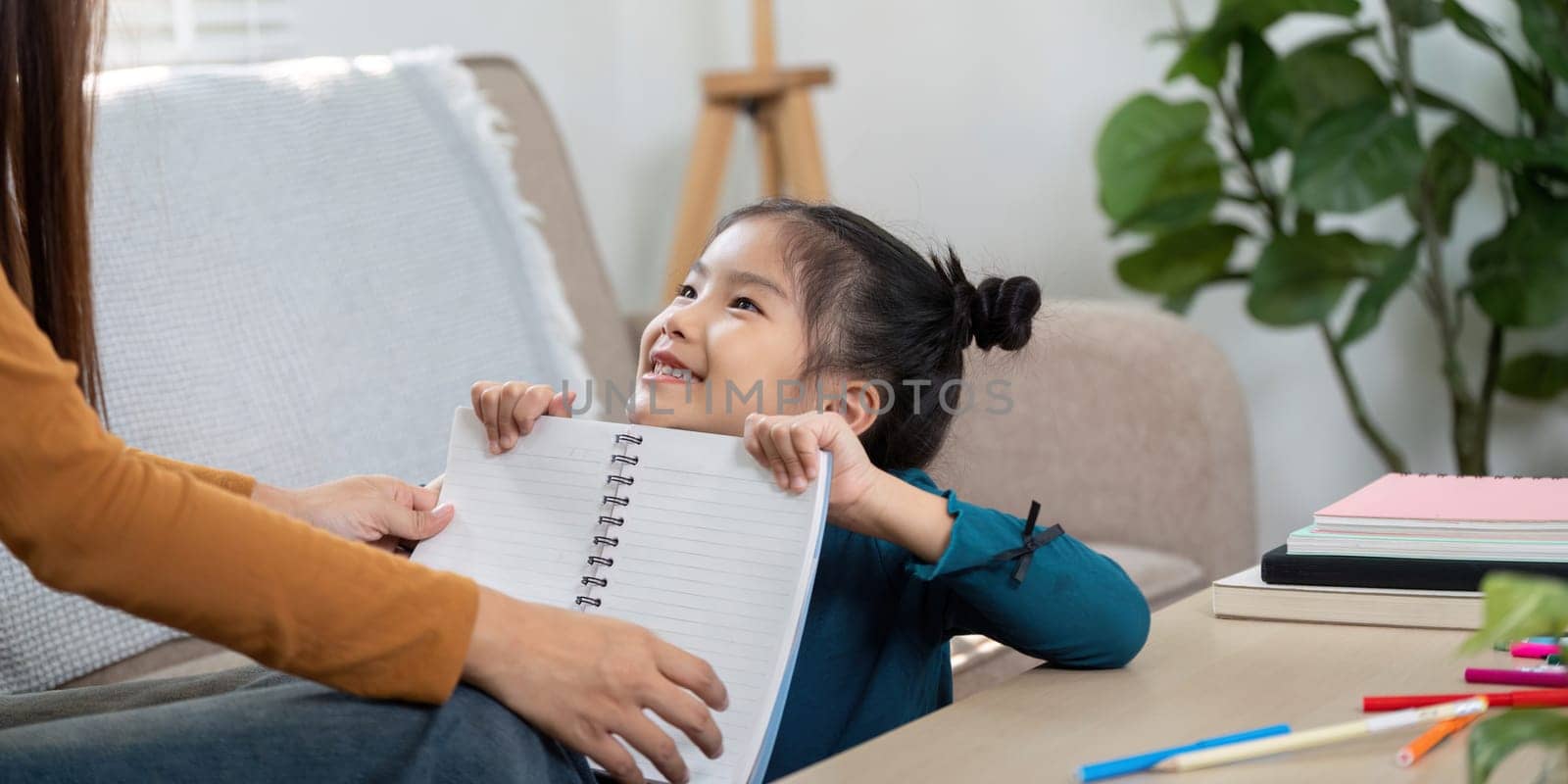 This capture shows a young girl shining with joy as she displays her work to her caregiver, highlighting the joy of learning together.