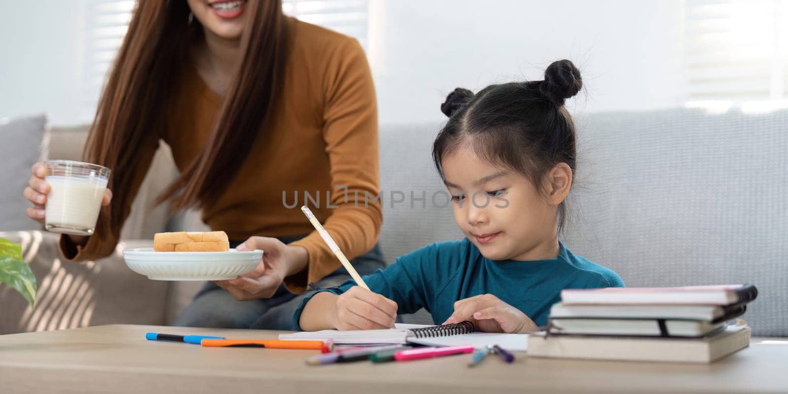 A thoughtful mother brings snacks and drinks to her daughter while she studies, encouraging a fun and creative atmosphere.