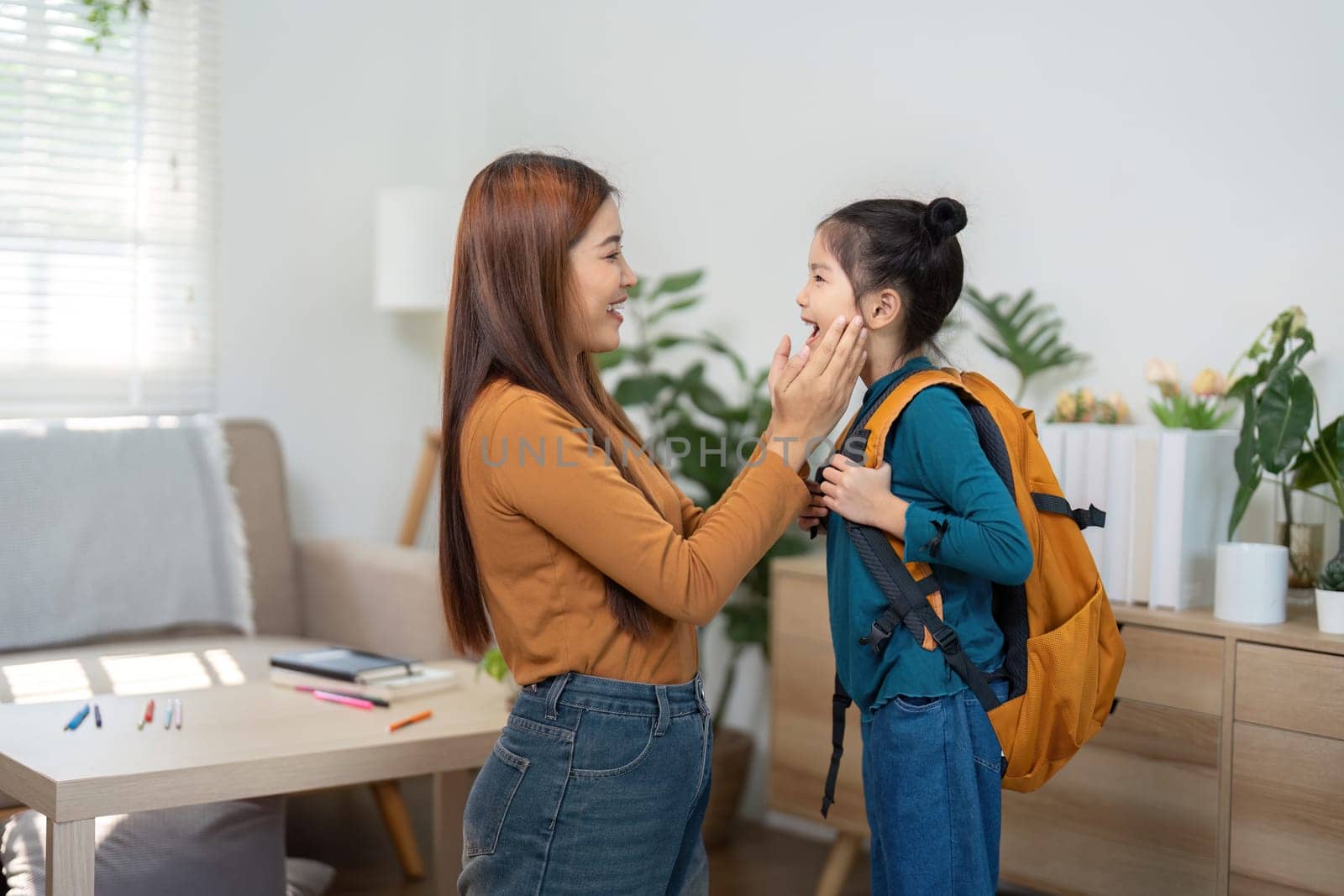 Moments filled with joy as a mother helps her daughter with her backpack, sharing smiles and excitement before school.