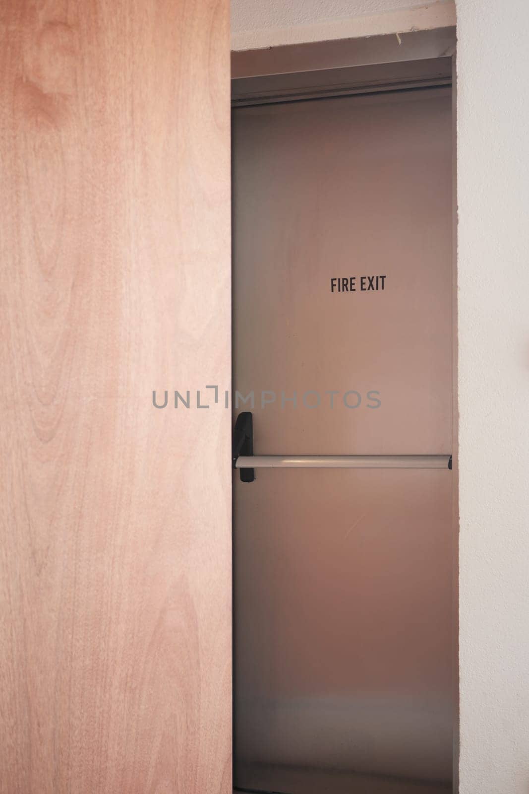 A fire exit door is slightly ajar in a clean hallway setting.