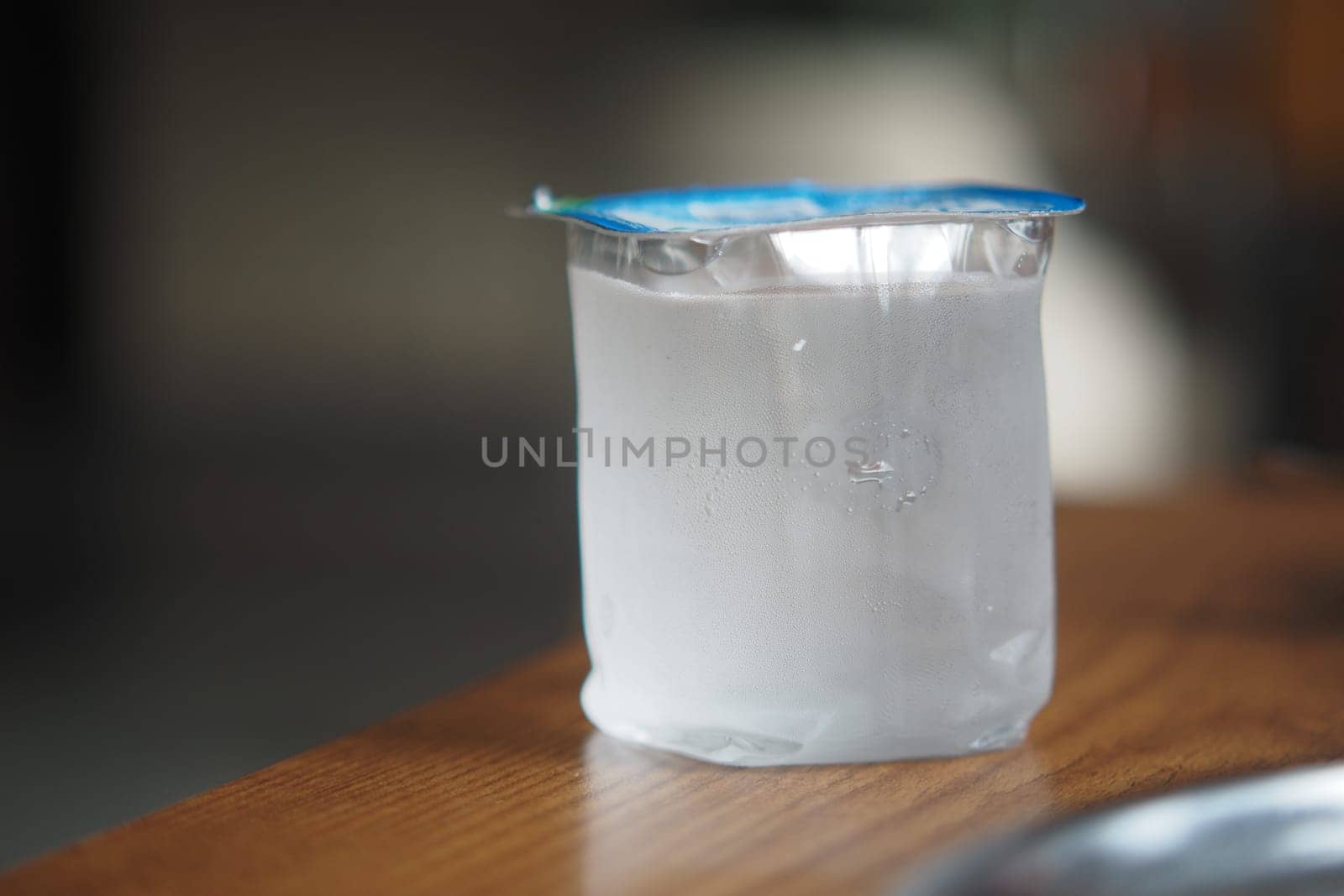 A container filled with water sits on a wooden table, exuding moisture.