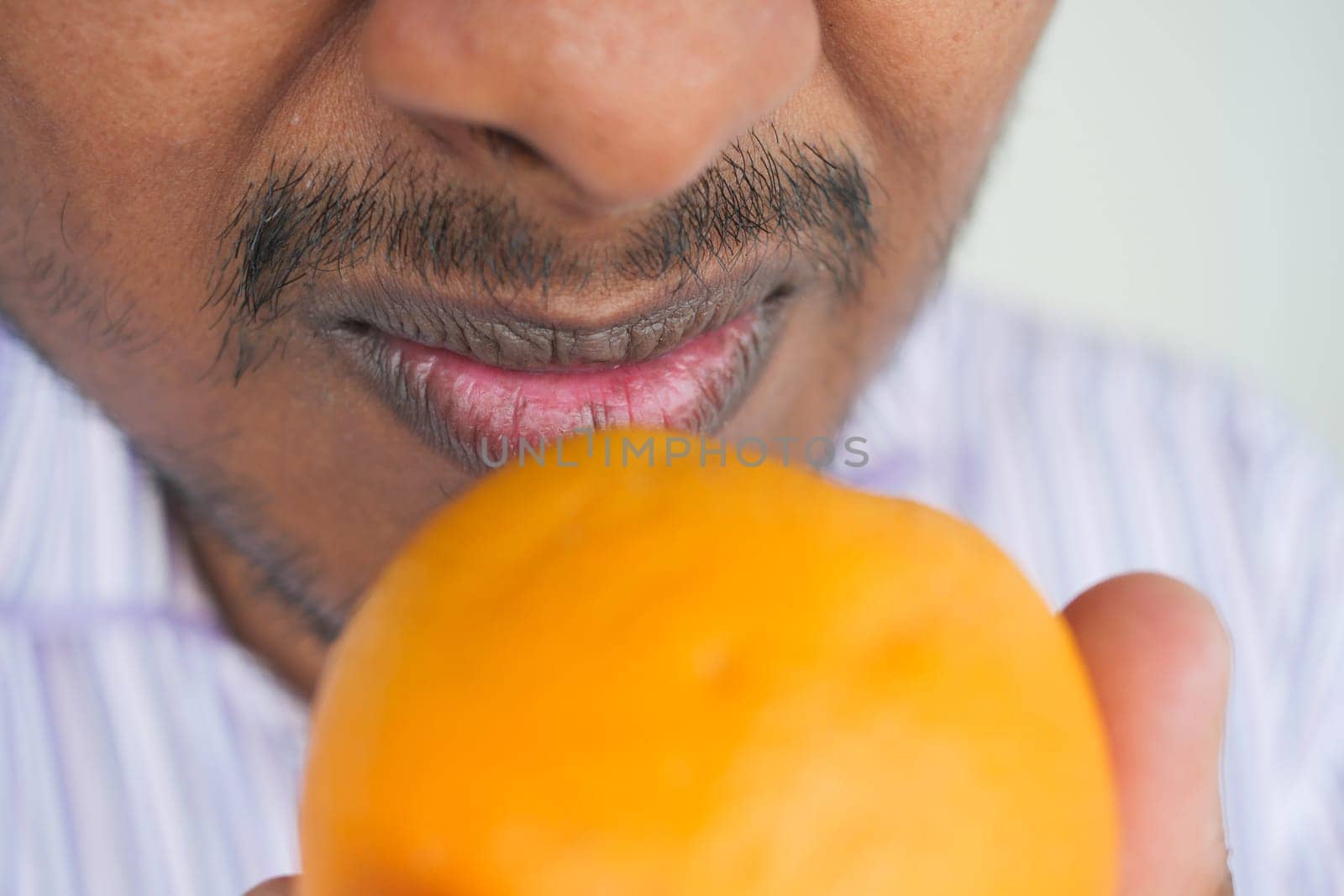 A man is inspecting a fresh orange with curiosity and interest.