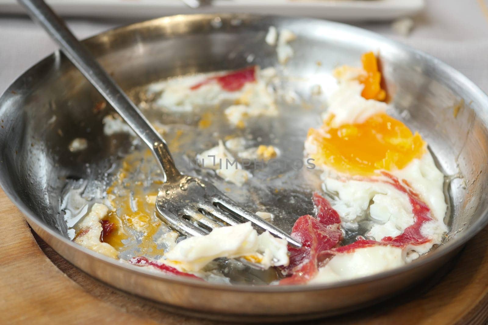 A plate shows remnants of a hearty breakfast with eggs and meat.