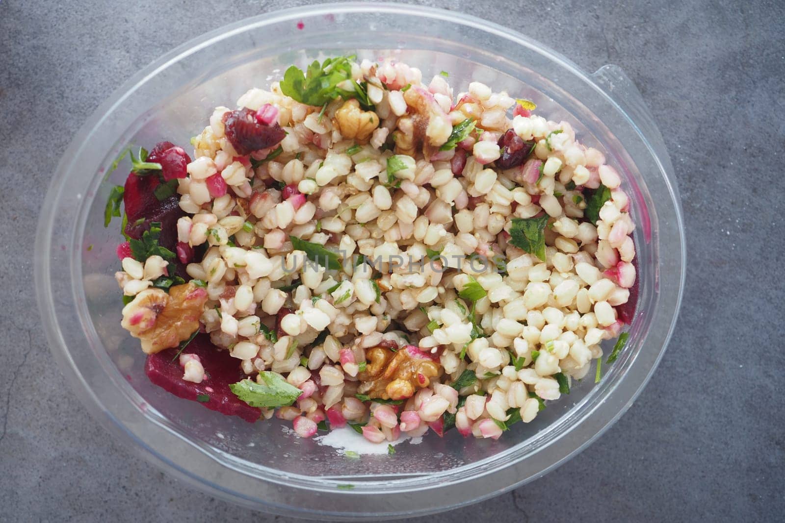 Fresh quinoa salad features walnuts, pomegranate, and herbs in a bowl.