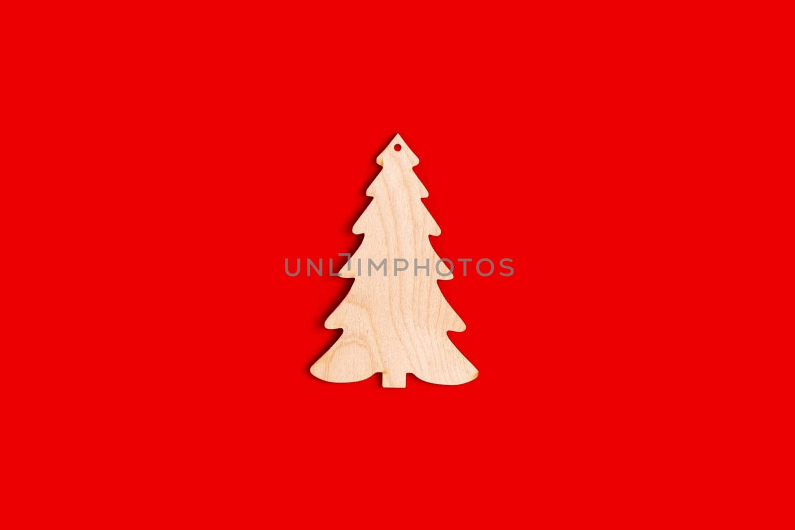 Flat natural unpainted wooden spruce shape on red background. Close up. Mock up