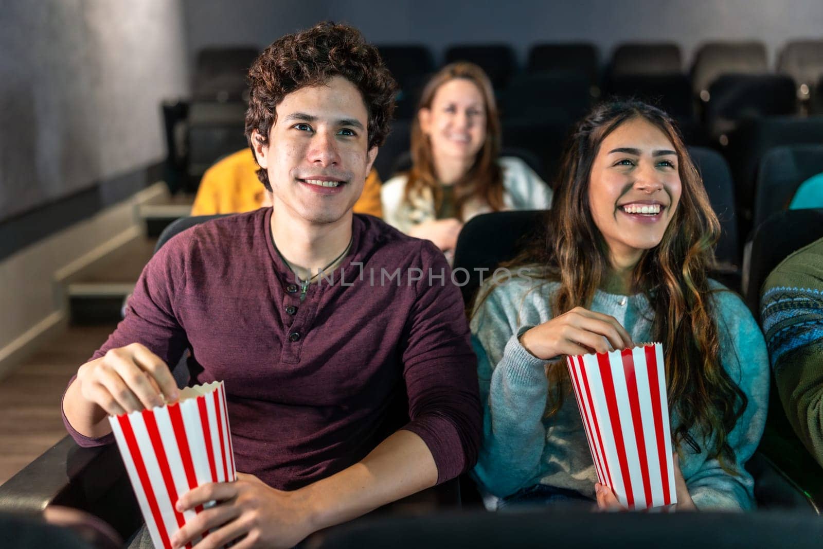 Happy couple enjoying a movie night at the cinema, sharing popcorn and smiles while immersed in the excitement of the big screen