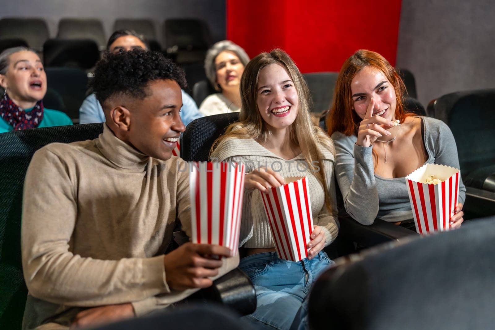 Young people enjoying a movie at the cinema, sharing laughter and popcorn, creating memorable moments together in a relaxed atmosphere