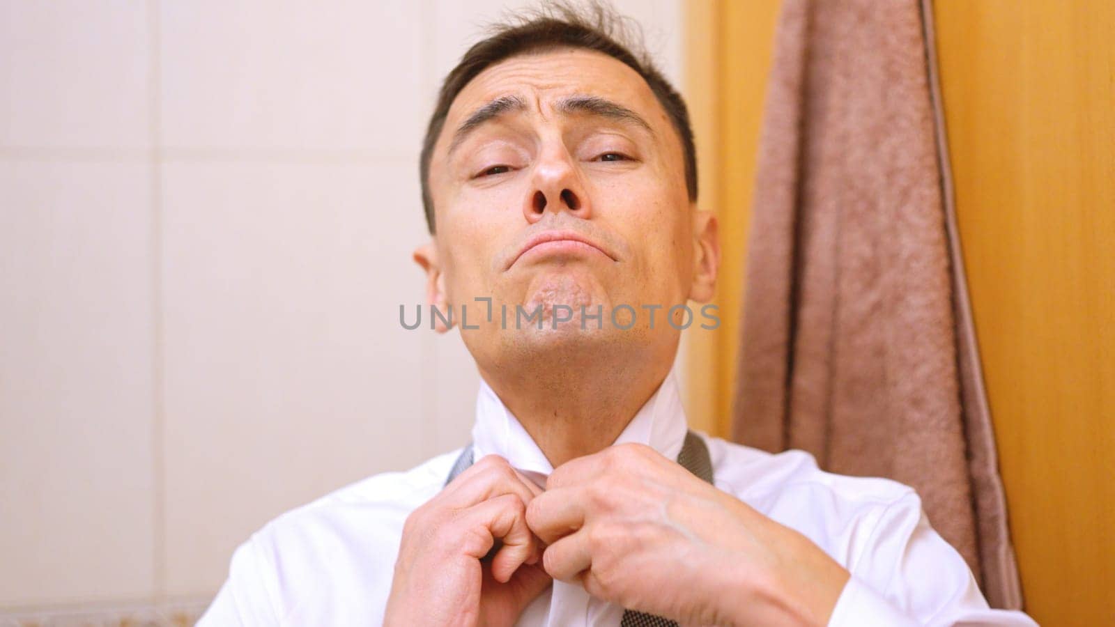 Millionaire businessman adjusting his tie in the morning in teh bathroom