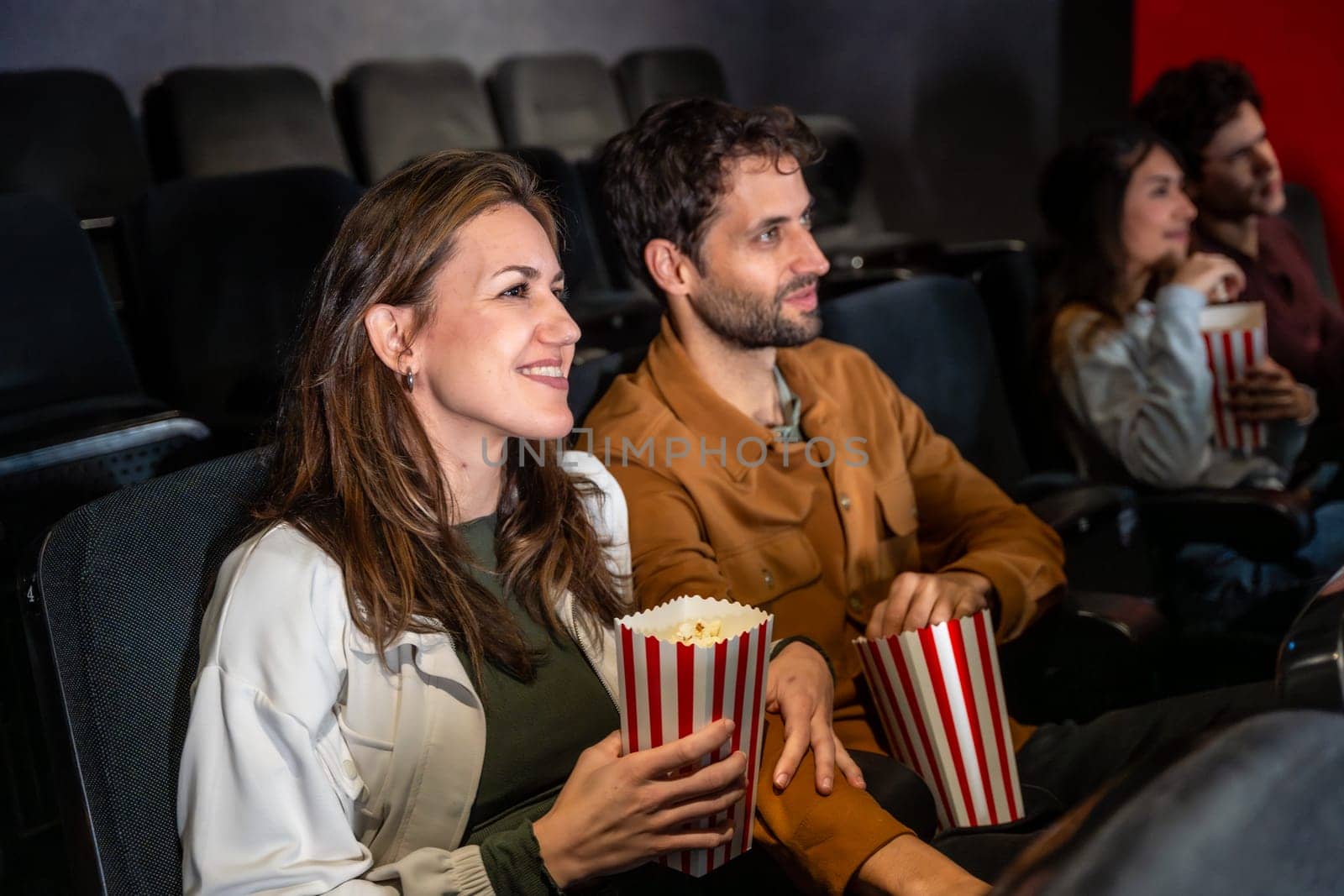 Group of friends enjoying a movie at the cinema, sharing laughter and popcorn while soaking in the excitement of the big screen