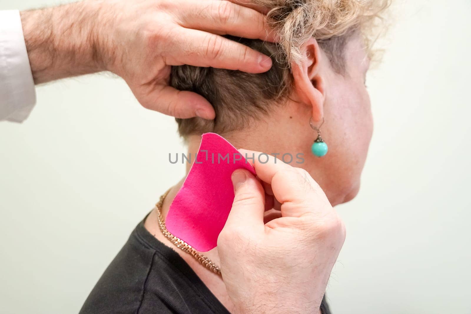 Kinesiology taping. Kinesiology tape on patient neck. Injured trapezius muscles treatment of young male athlete.