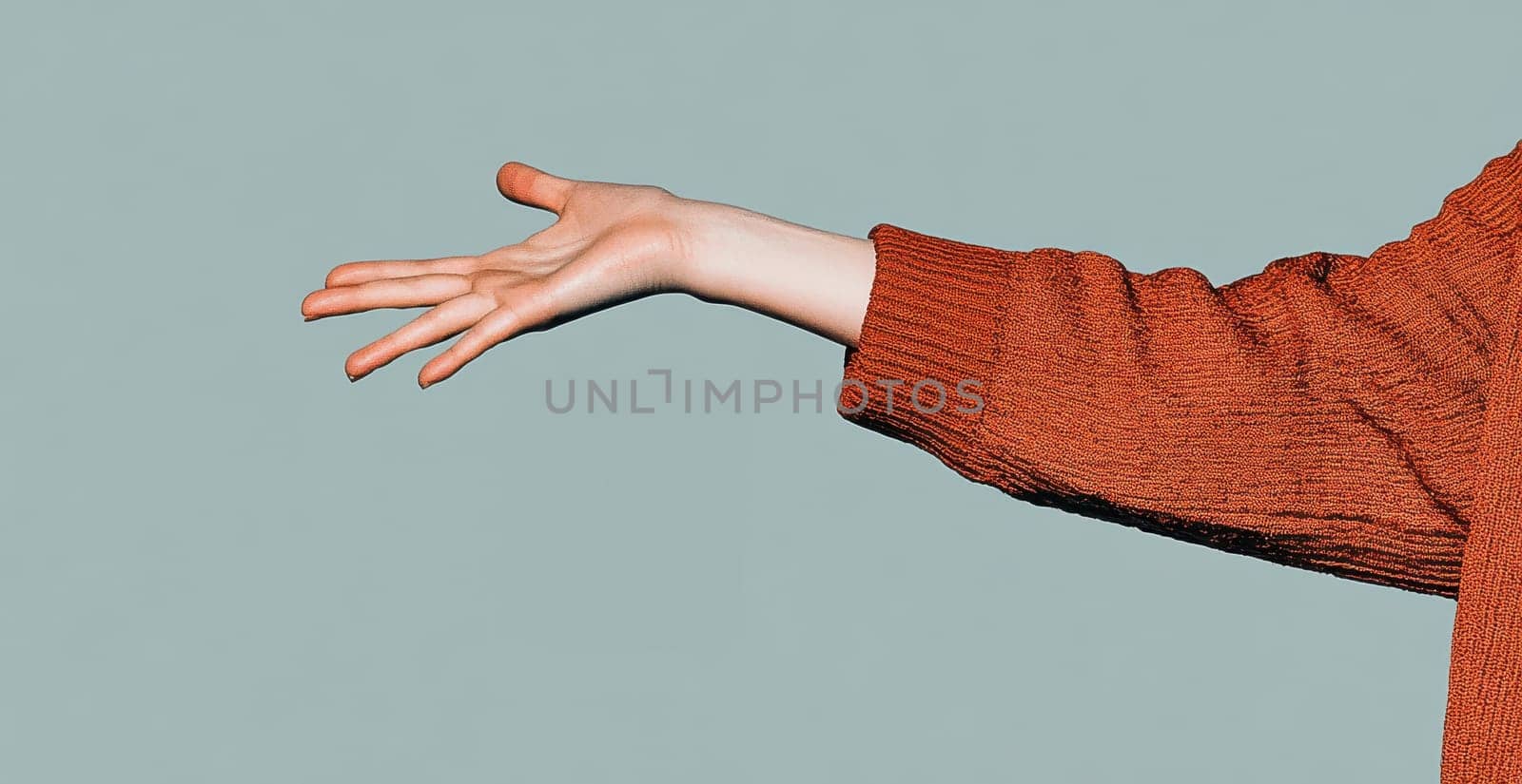 A woman's hand, in a burnt orange sweater, extends outward, palm up, against a muted teal background.
