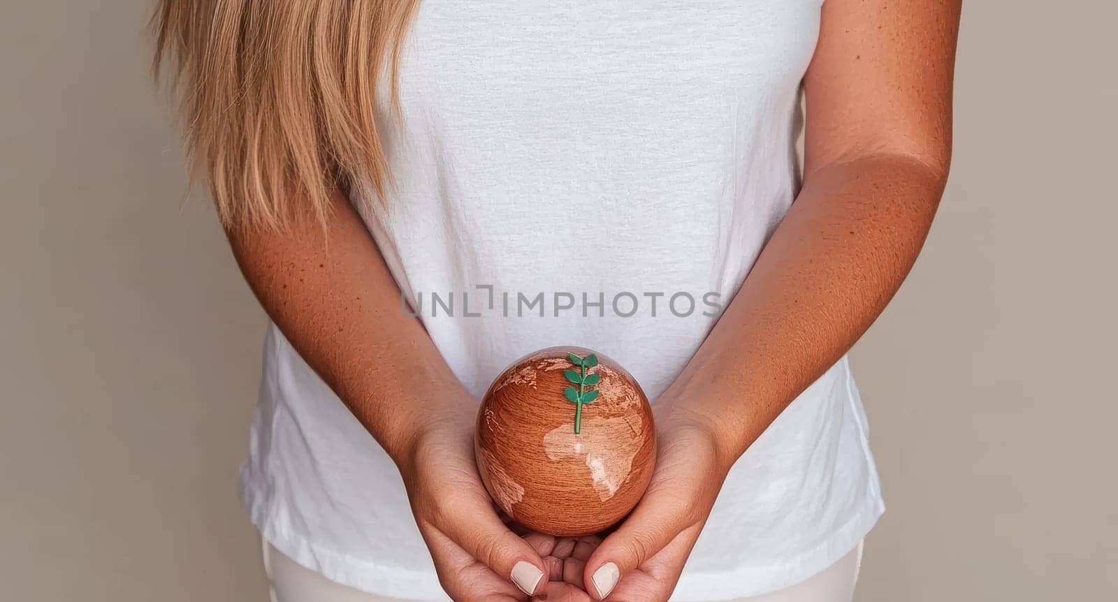 A woman holds a small wooden globe with a green sprout, symbolizing environmental care and sustainability.