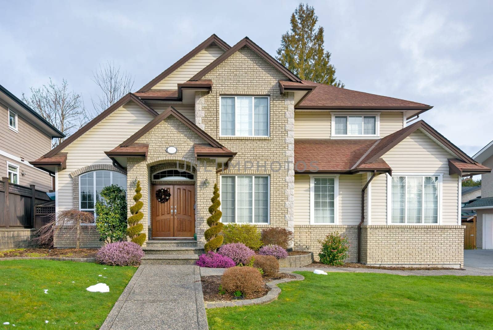 A perfect neighborhood. Nicely landscaped front yard of luxury residential house with paved pathway to the entrance. Luxury residential house