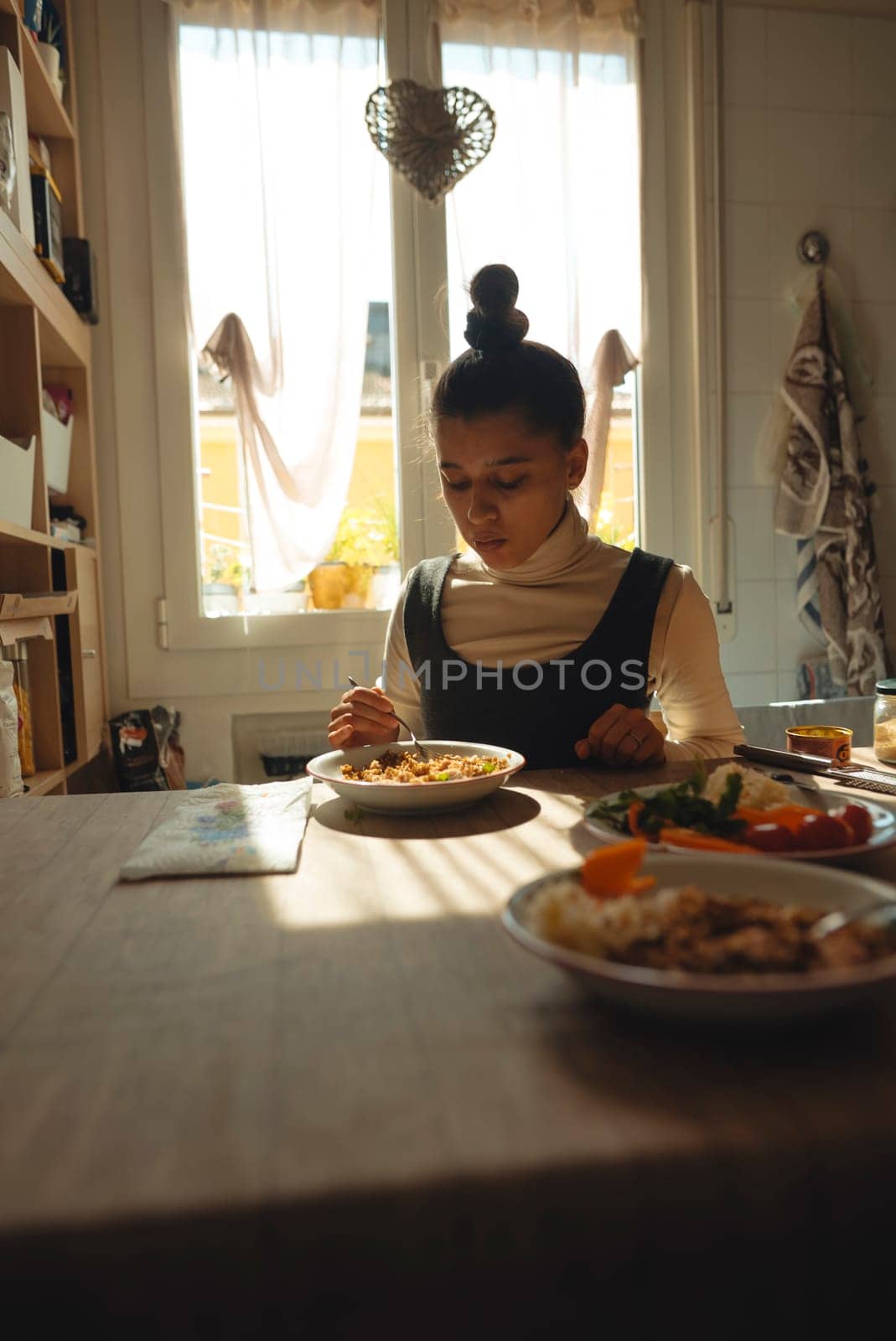 A woman is comfortably sitting at a table, savoring her delicious meal in a warm and inviting dining area