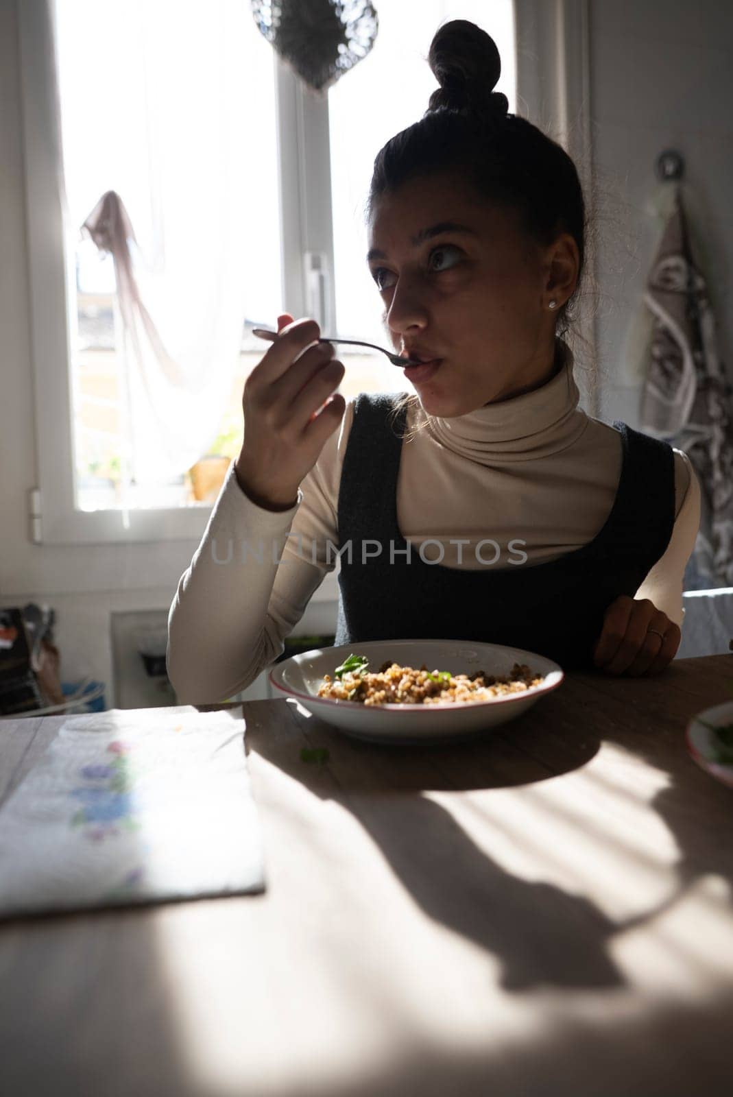 A contemplative woman savoring her delicious meal, with soft light casting intriguing shadows around her