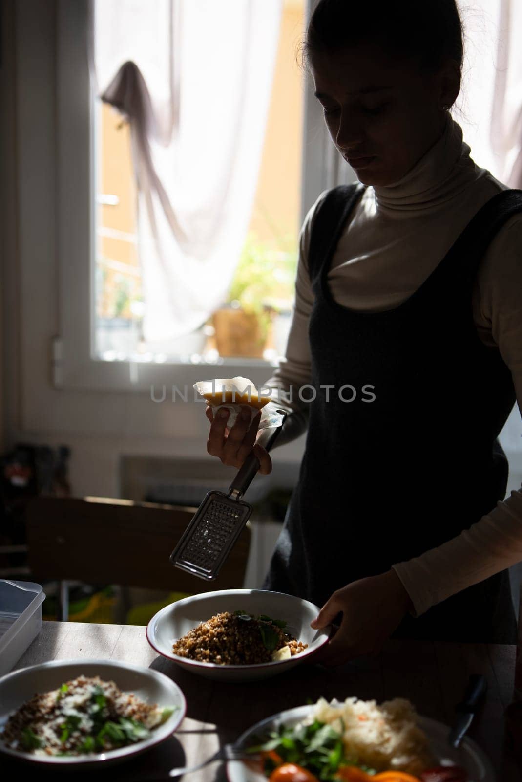 A woman plating a delicious dish, displaying her cooking artistry in a warm kitchen filled with fresh ingredients