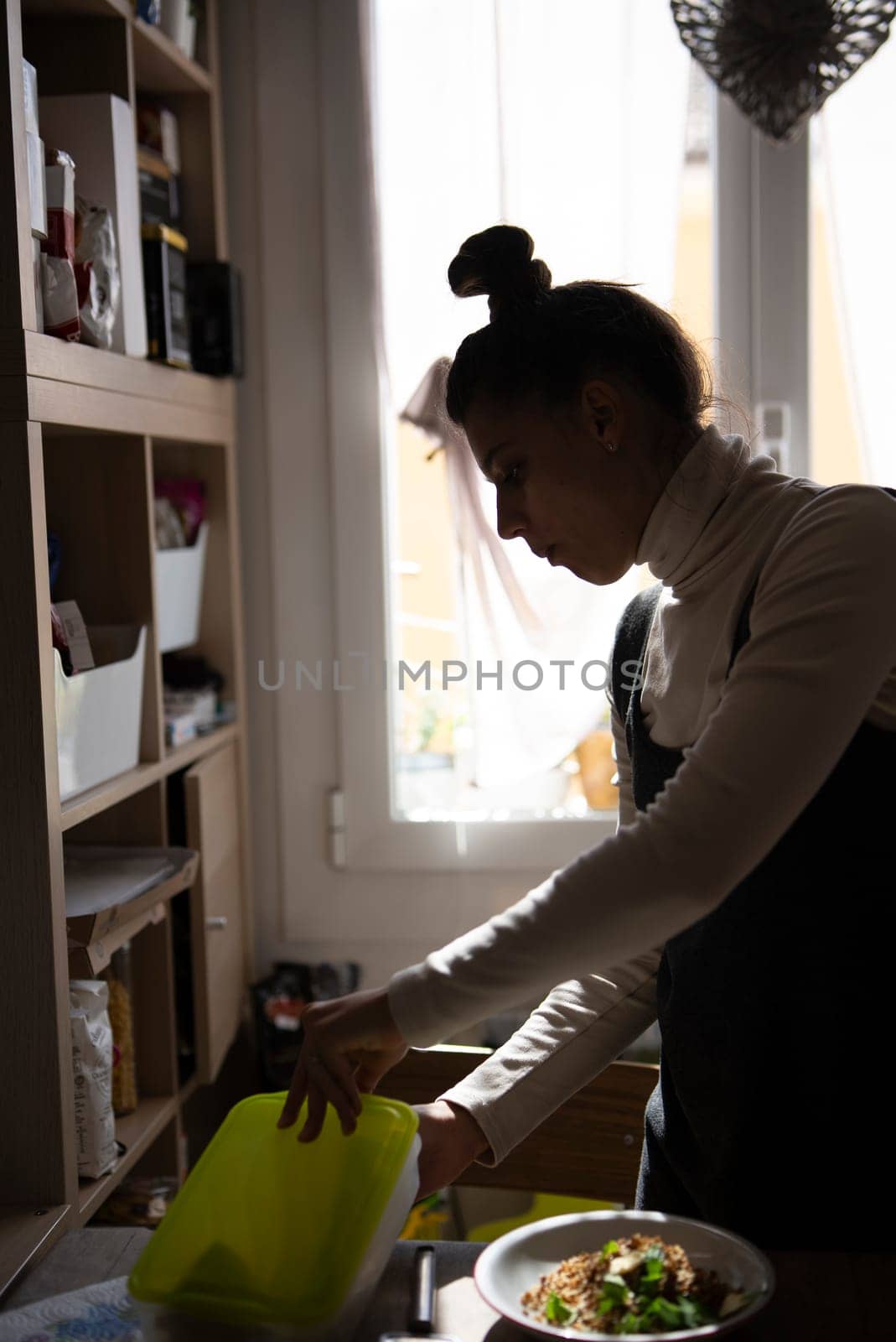 A woman enthusiastically engages in the meal preparation process, showcasing a modern, cozy kitchen ambiance