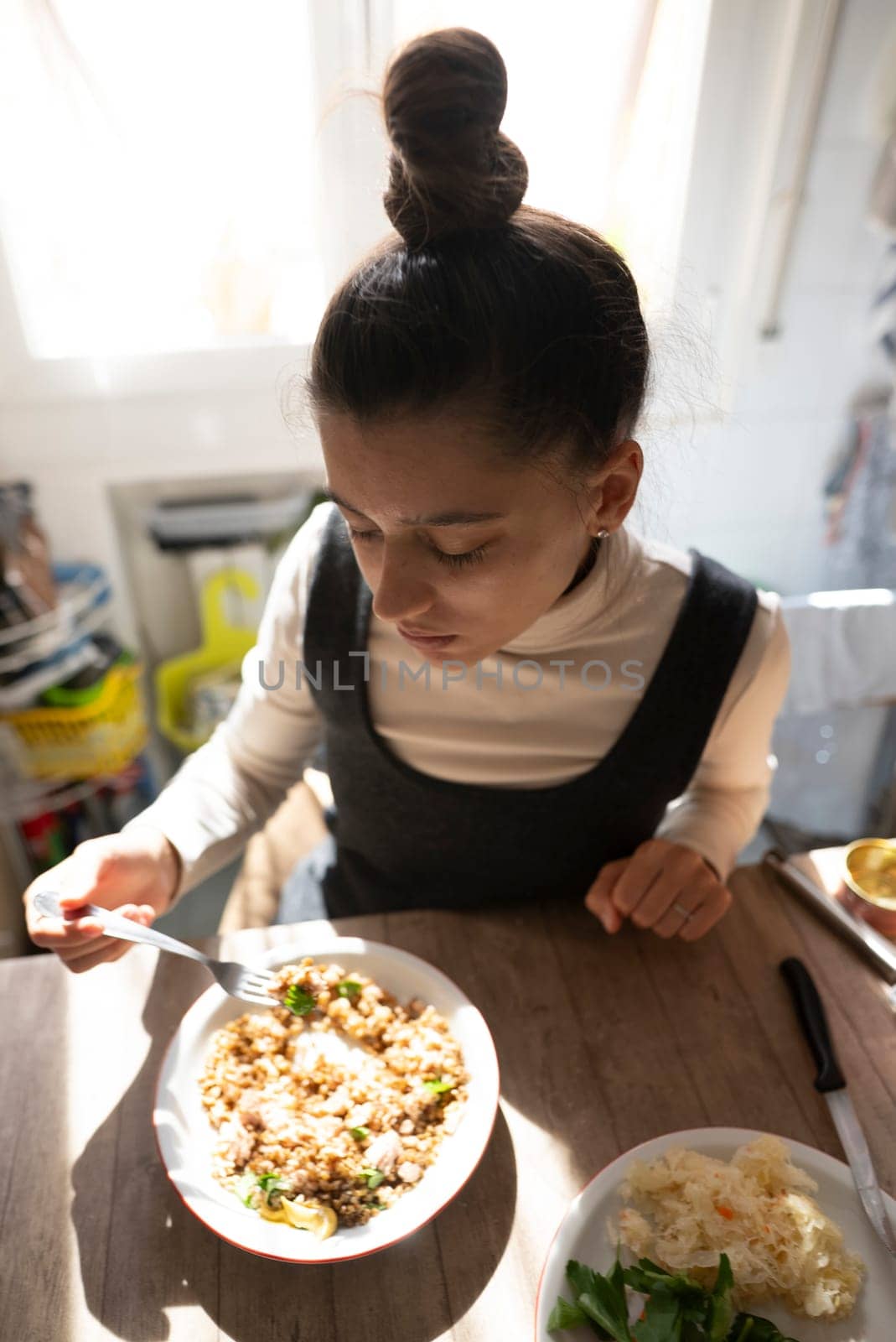 A woman is enjoying and savoring a delicious and nutritious bowl of wholesome food at a cozy kitchen table