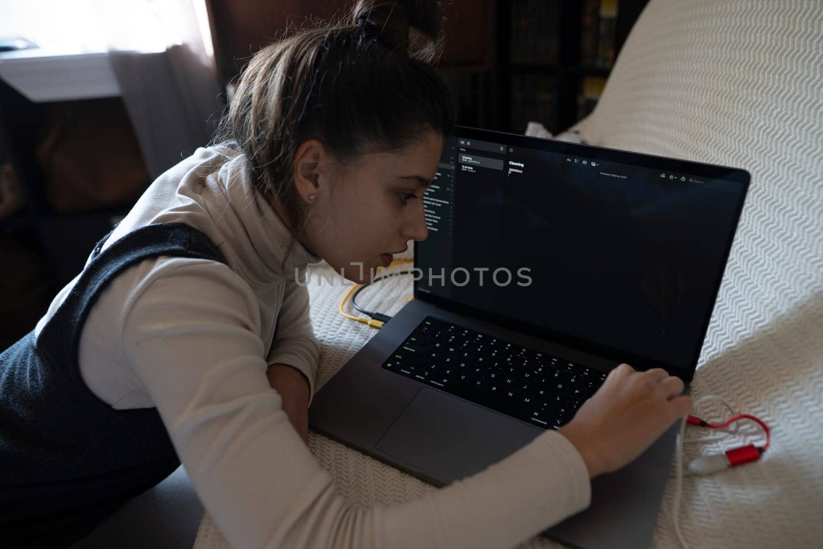 A dedicated young woman, fully focused on her work, types intently at her laptop in a peaceful, serene environment