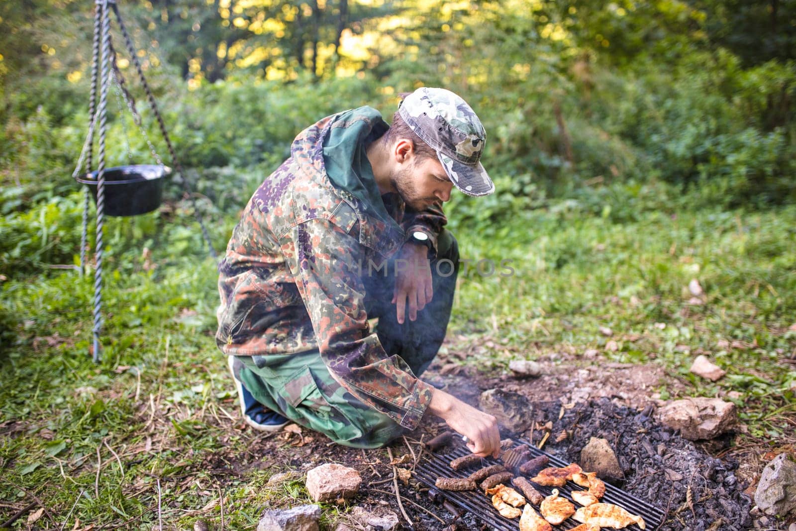 Hunter grilling meat on campfire during a hunting trip in forest