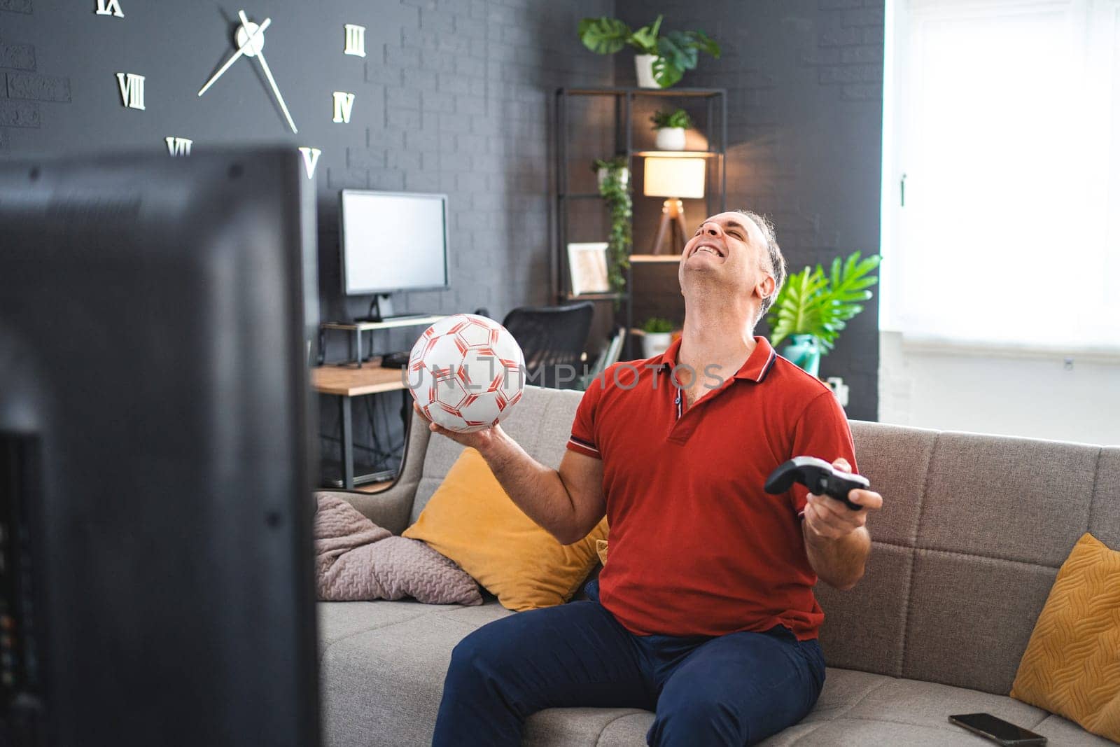 Middle age Caucasian man playing soccer video game at home.