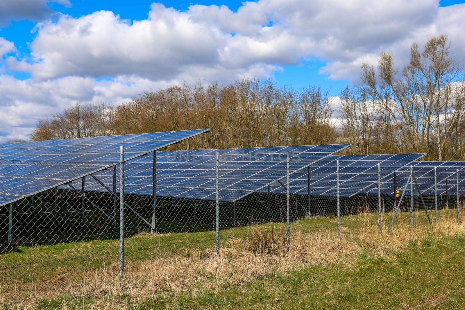 Photovoltaic panels capturing sunlight behind a metal fence, generating renewable energy for a sustainable future