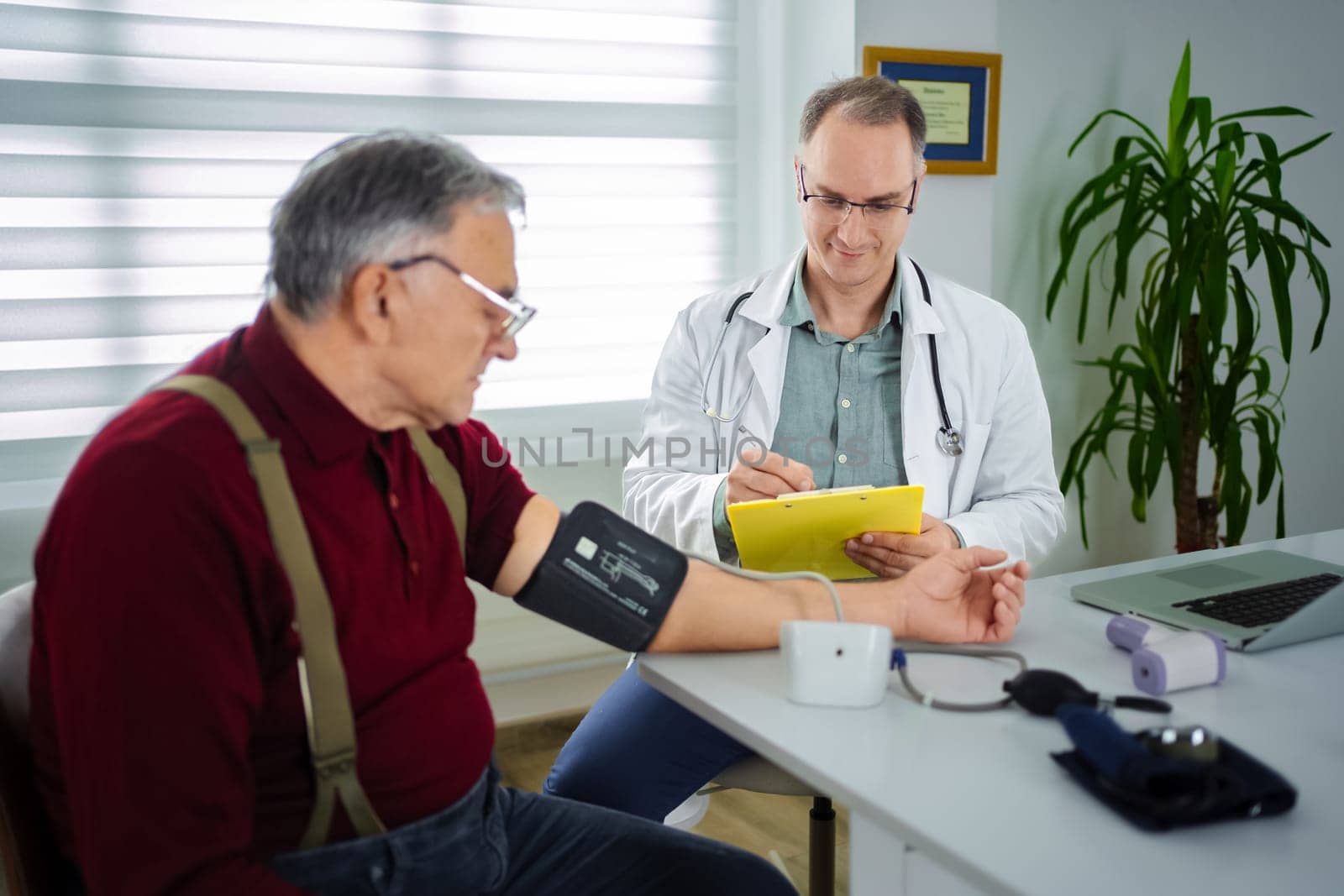 An elderly man receives a blood pressure check from his doctor.